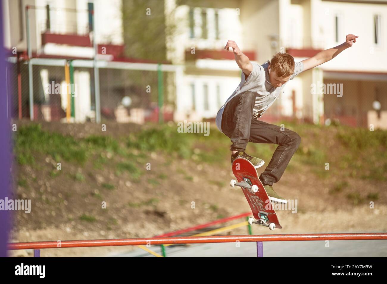 Un skate-board adolescent fait un tour d'ollie dans un skatepark à la périphérie de la ville Banque D'Images