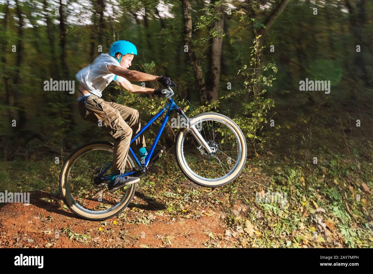 un jeune gars dans un casque vole atterri sur un vélo après avoir sauté d'un éjecteur Banque D'Images