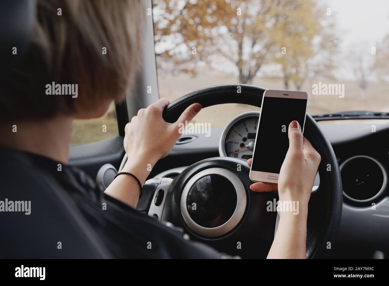 fille conduisant une voiture en tapant du texte sur le téléphone et regarder la fenêtre Banque D'Images