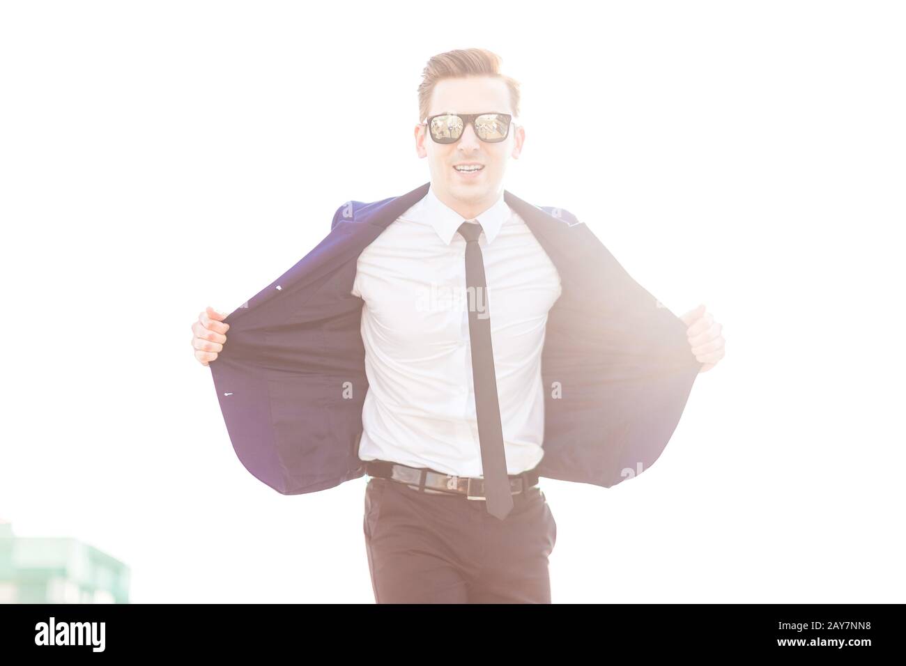 Joli petit butunessman en costume bleu et lunettes de soleil se tiennent o Banque D'Images