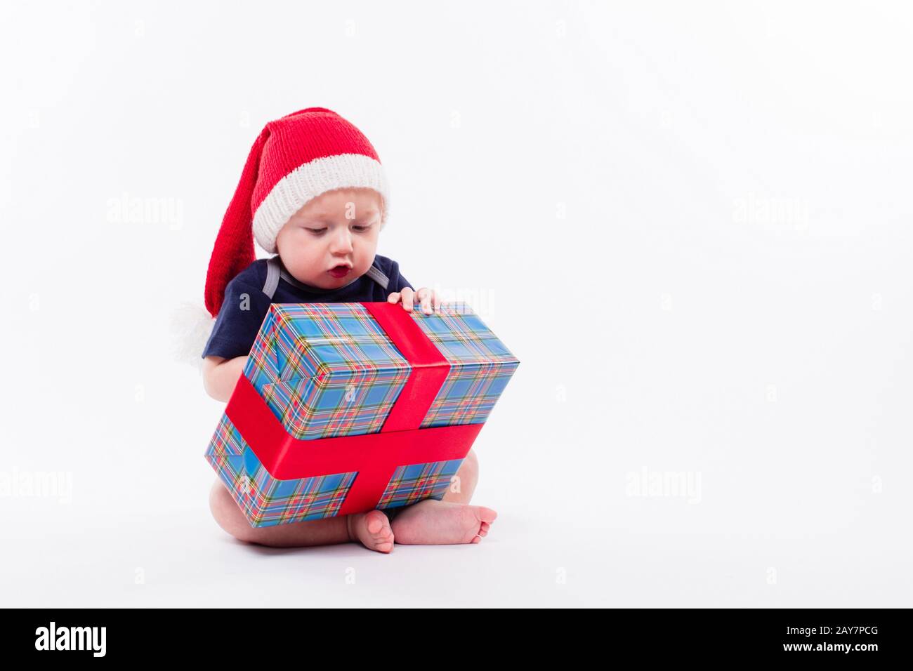 Un petit enfant mignon est assis dans une casquette rouge du nouvel an sur le nègre blanc Banque D'Images