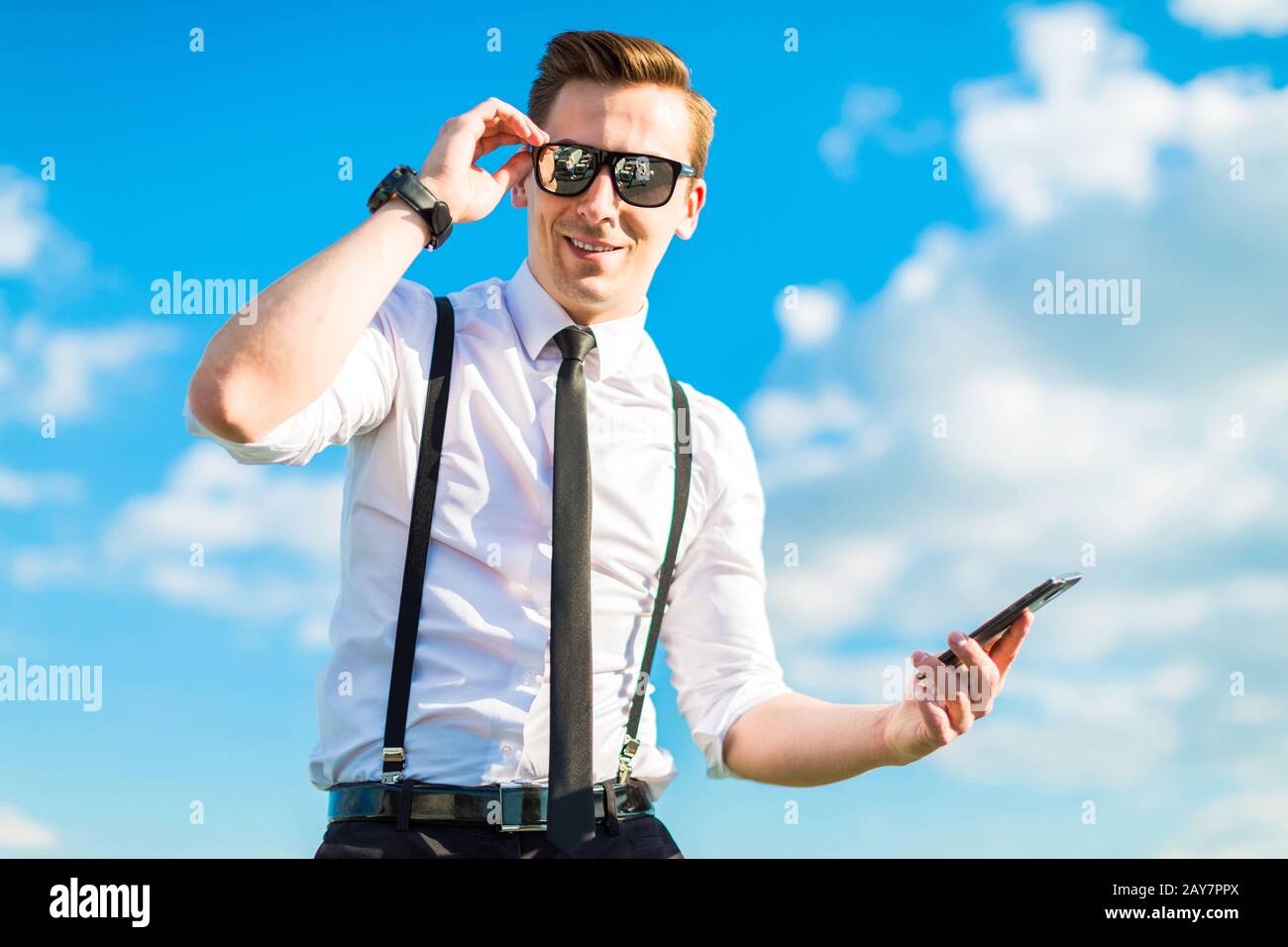 Joli butunessman en chemise blanche, cravate, bretelles et lunettes de soleil Banque D'Images