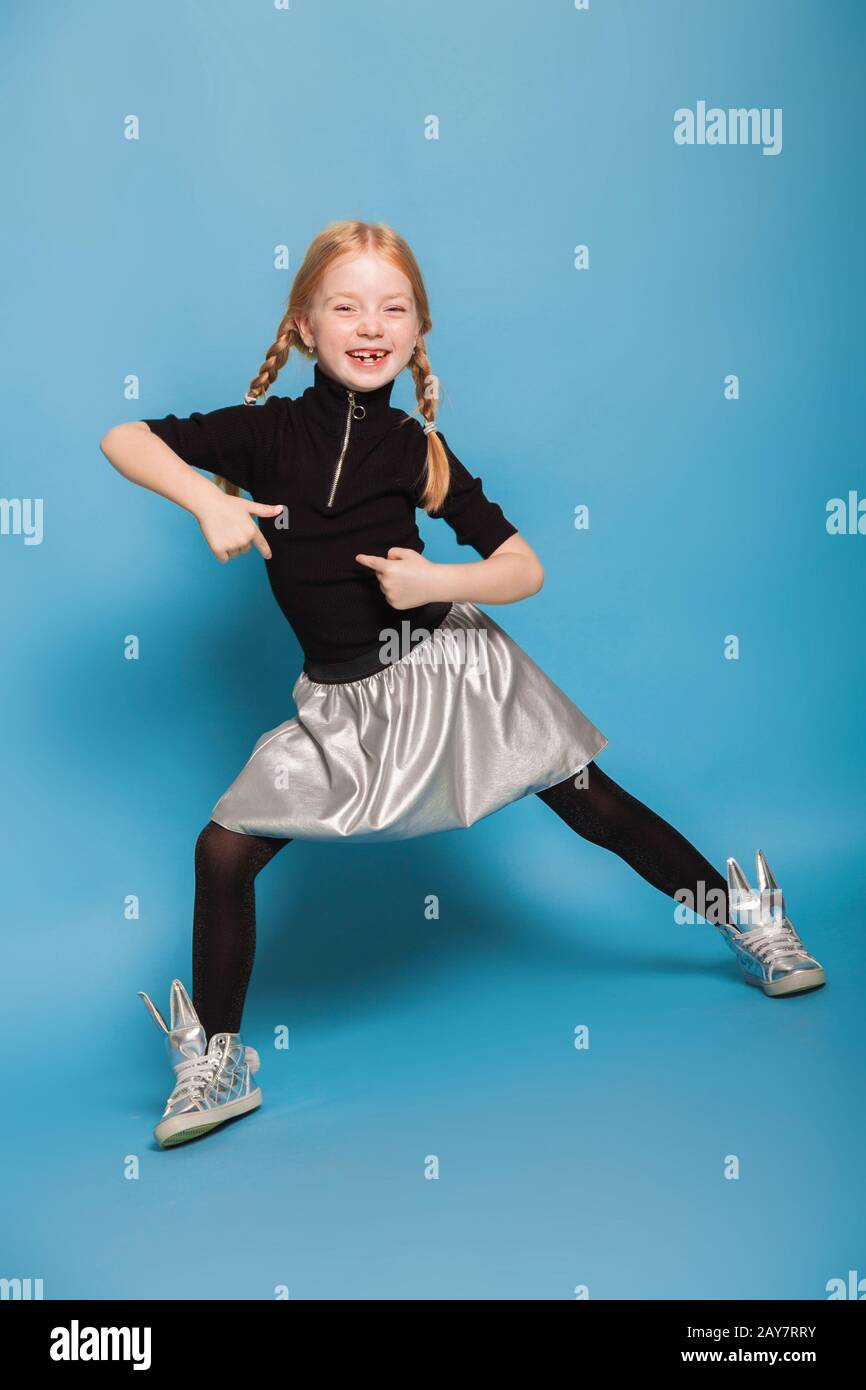 Petite fille aux tresses en vêtement élégant sur fond bleu Banque D'Images