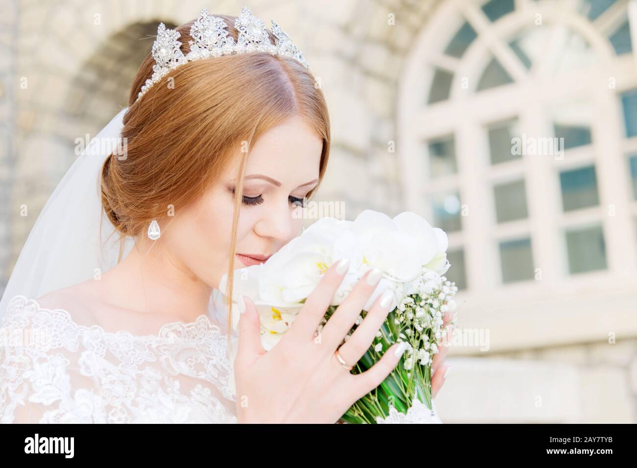 Une jeune mariée dans une robe blanche ronfle son bouquet de mariage qui est soigneusement tenu par ses mains Banque D'Images