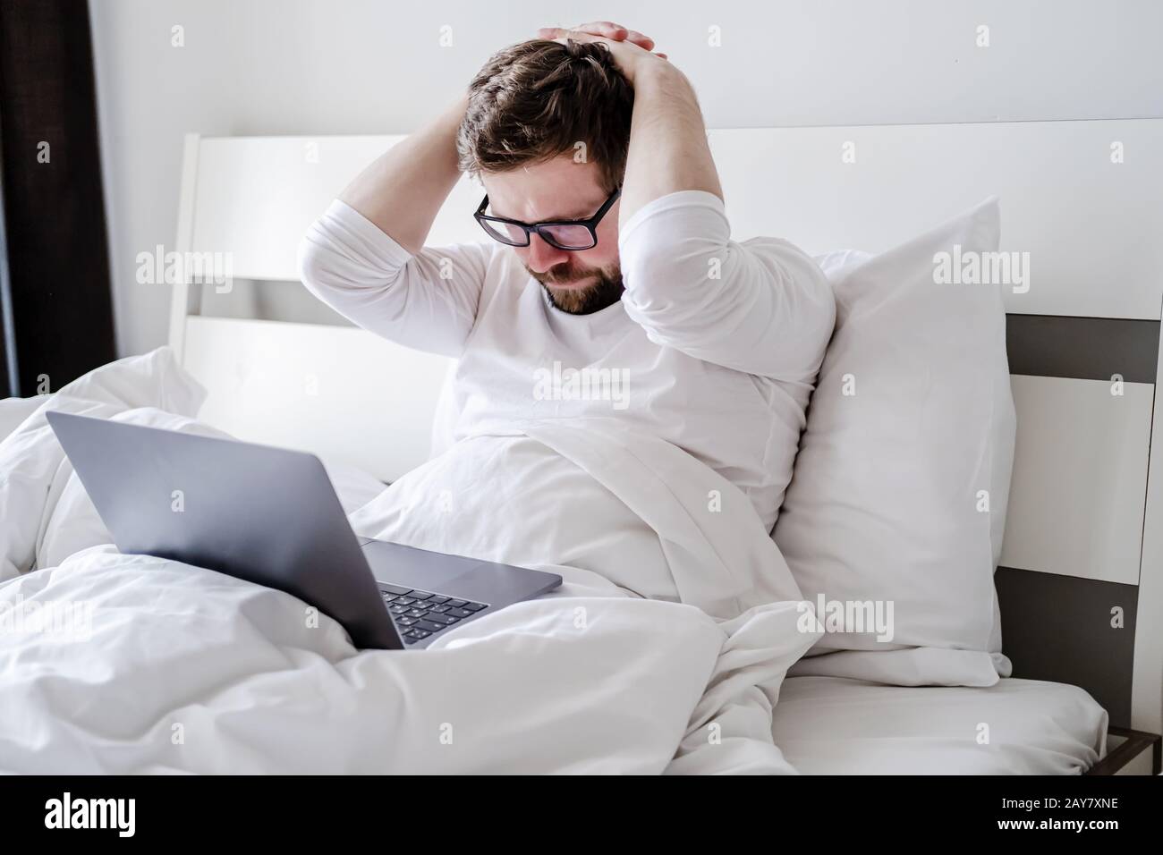 Homme en pyjama est contrarié, il a travaillé toute la nuit avec un  ordinateur portable dans le lit et n'a pas terminé le projet Photo Stock -  Alamy