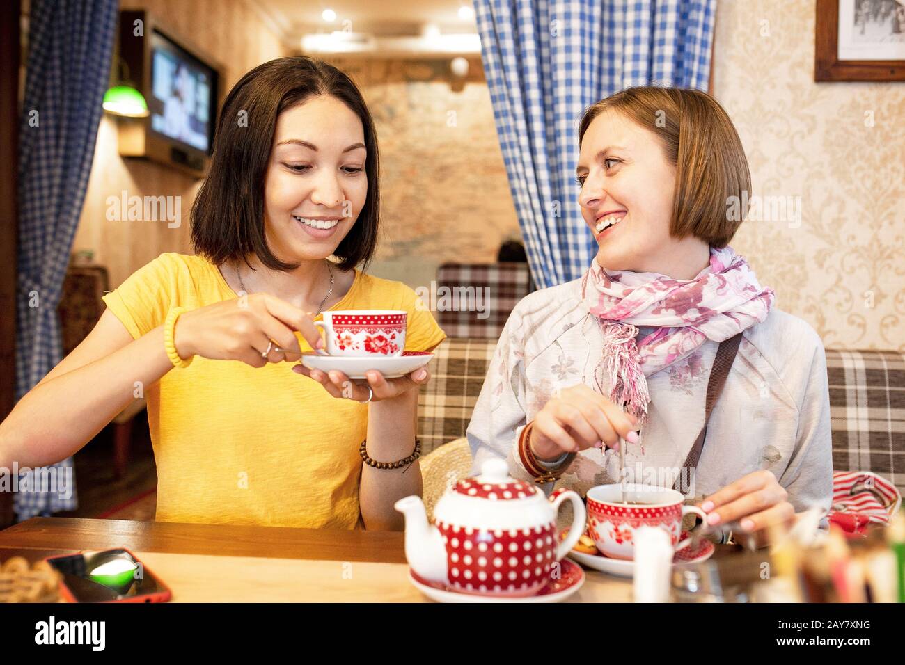 Des amis parlent et rient tout en prenant une tasse de thé dans un café Banque D'Images