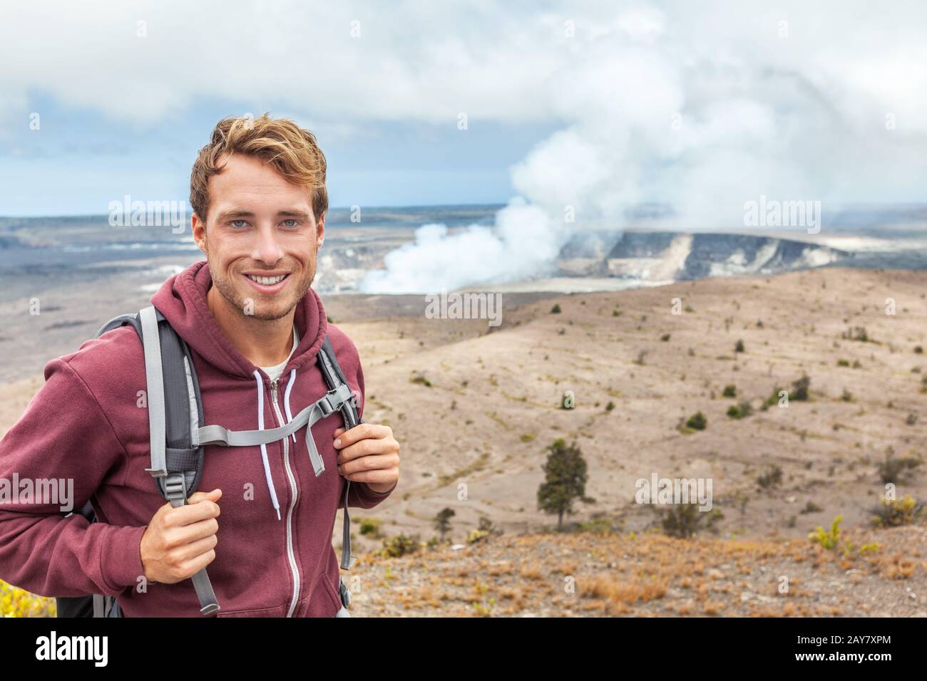 Homme touristique du volcan Hawaï au cratère de Halemaumau à la caldeira de Kilauea dans le parc national des volcans d'Hawaï, grande île avec des nuages volcaniques et cendres de l'éruption. Banque D'Images