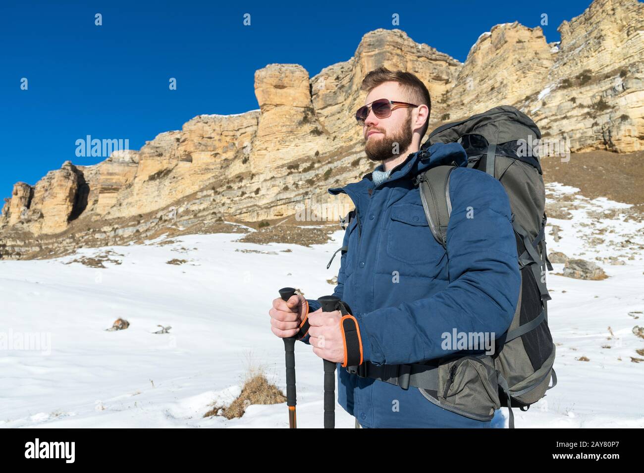 Portrait D'UN hipster barbu avec un sac à dos et dans des lunettes de soleil avec un grand sac à dos sur ses épaules se tient avec des bâtons pour Nordi Banque D'Images