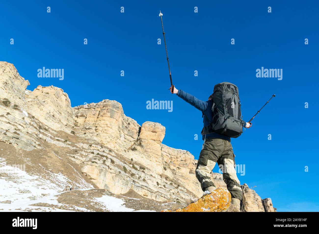 Hiker hippster avec un grand sac à dos au pied des roches épiques déclare intention de gagner. Banque D'Images