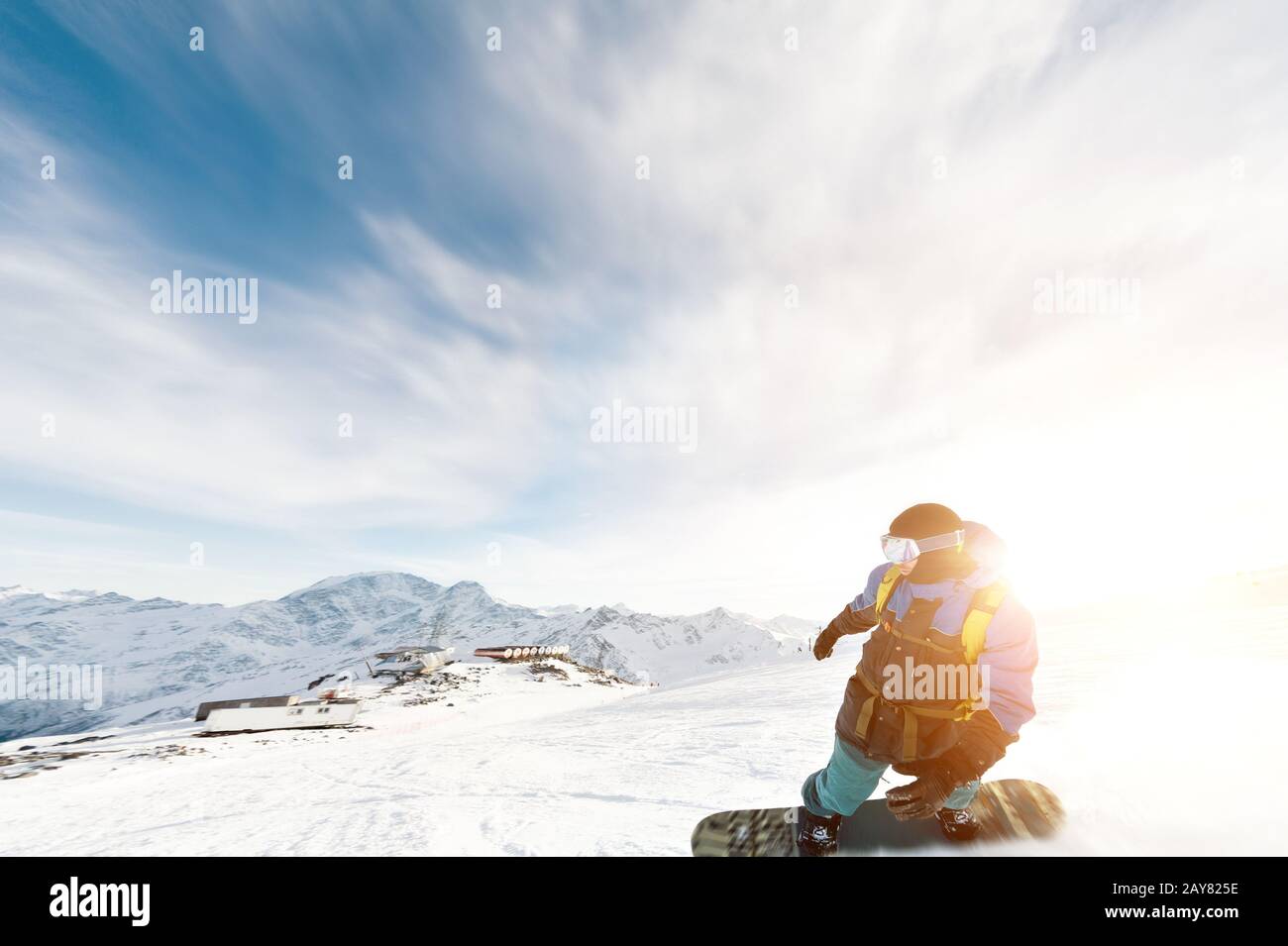 Un snowboarder dans un masque de ski et un sac à dos est sur une pente  enneigée laissant derrière une poudreuse contre le ciel bleu A Photo Stock  - Alamy