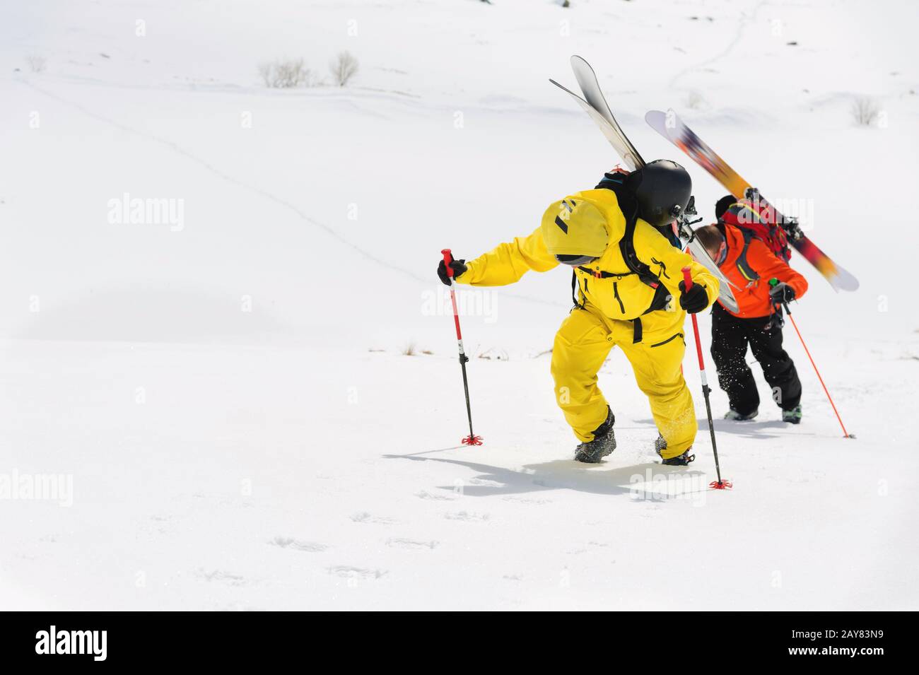 deux freerider à ski grimpent la pente en poudre de neige profonde avec l'équipement à l'arrière fixé sur le sac à dos. Banque D'Images