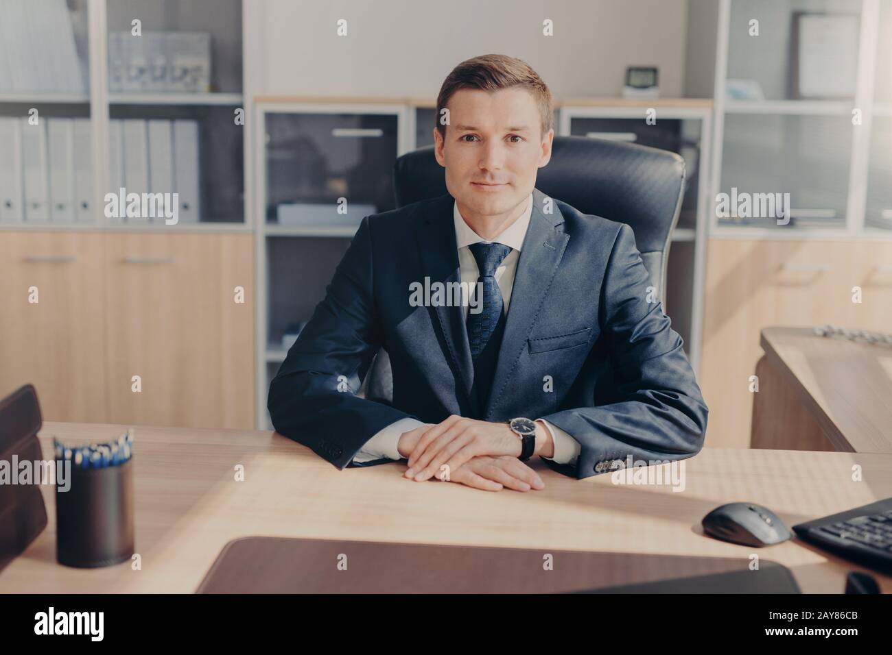 Portrait d'un homme d'affaires prospère séduisant porte un costume noir, une chemise blanche avec cravate, se trouve dans son propre cabinet, attend que les partenaires d'affaires me commencent Banque D'Images