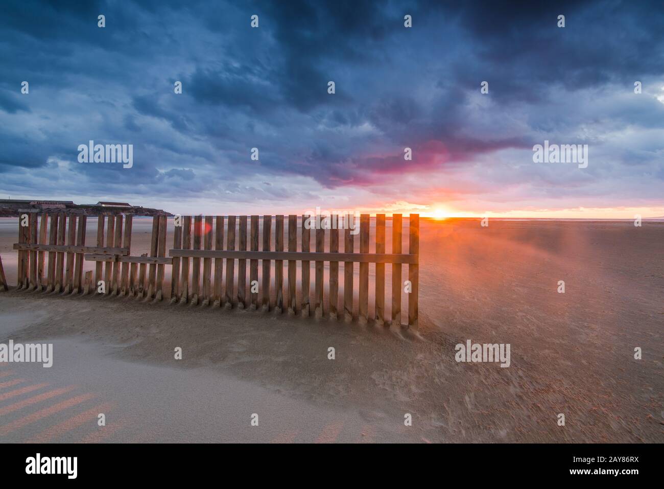 Clôtures en bois sur la plage de Tarifa, coucher de soleil après une tempête dramatique Banque D'Images