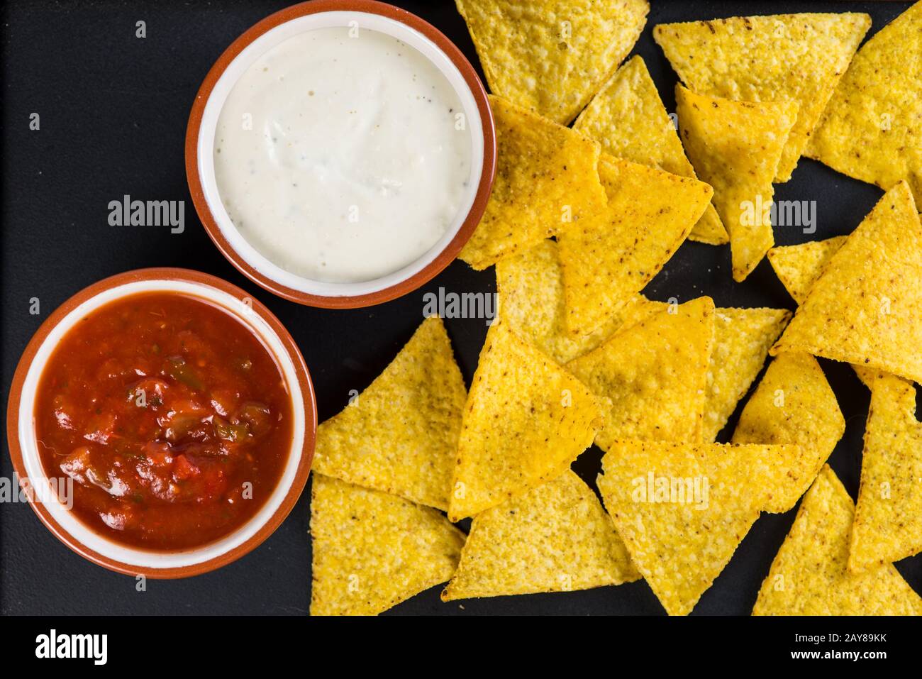 nachos mexicains de la cuisine de rue avec salsa et crème trempée sur fond noir Banque D'Images