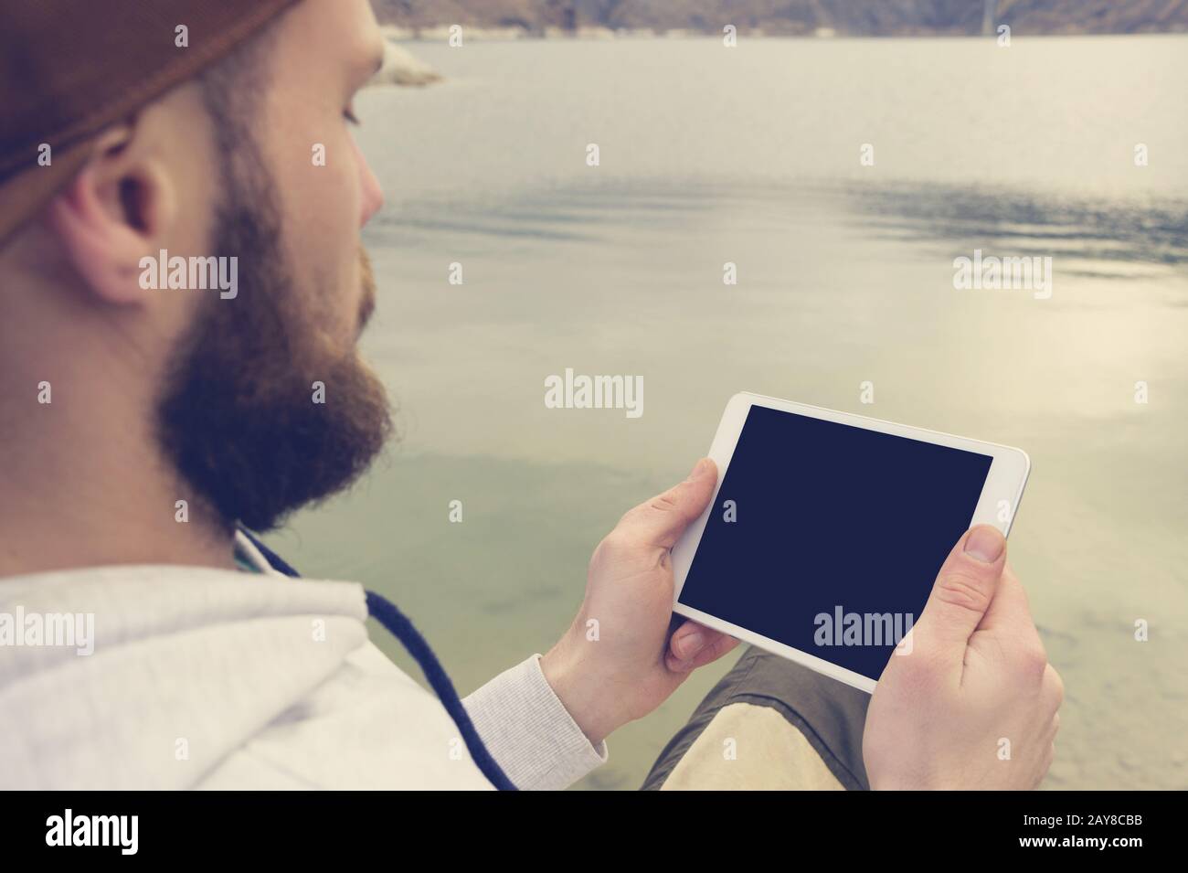 Gros plan d'une horde dans une casquette brune en plein air tient un Tablet pc blanc dans ses mains. Un homme barbu regarde la tablette. OTS Banque D'Images