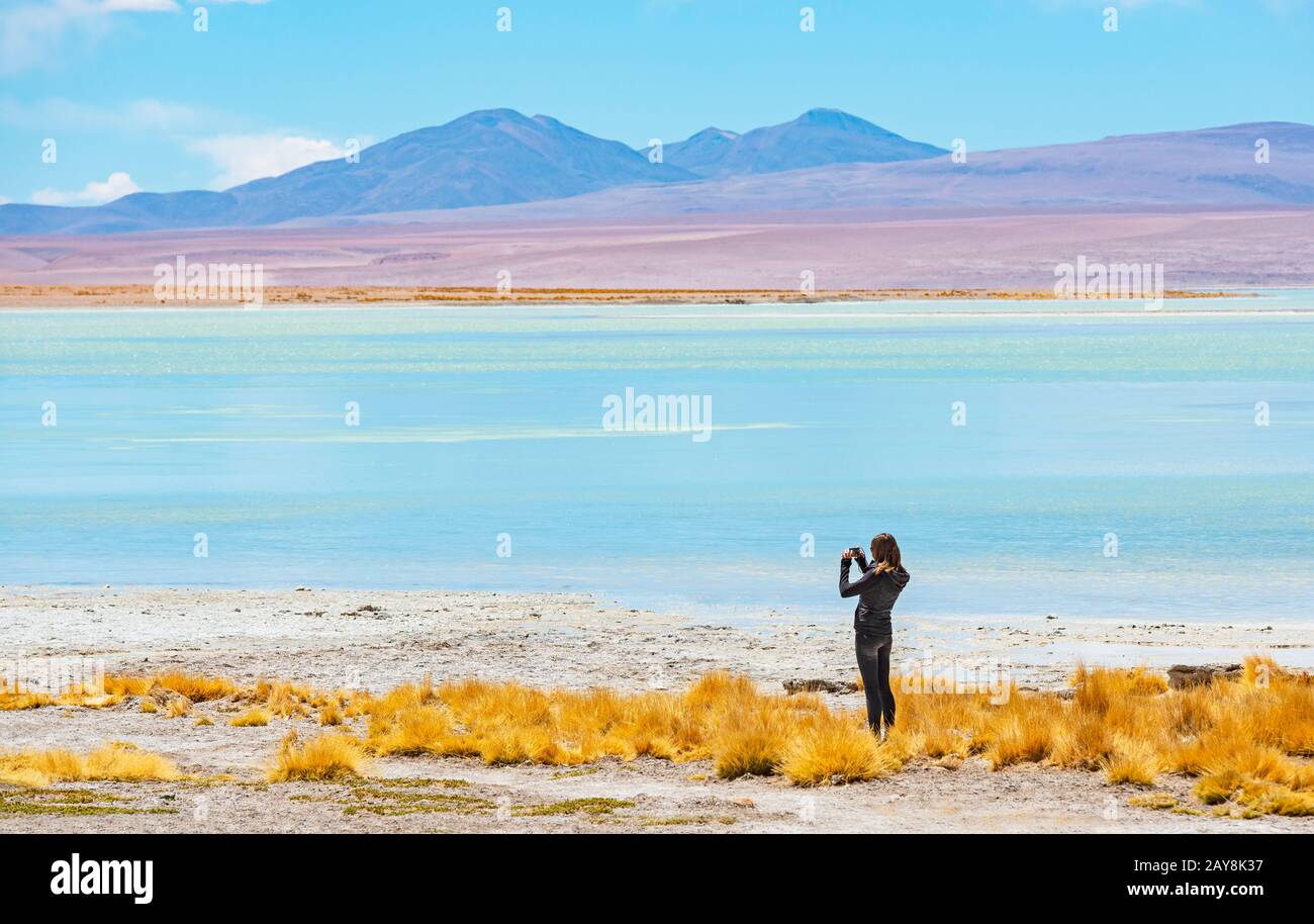 Jeune femme routard prenant des photos avec son téléphone de la lagune Chalvari près de la plate de sel d'Uyuni (Salar de Uyuni), Bolivie. Banque D'Images