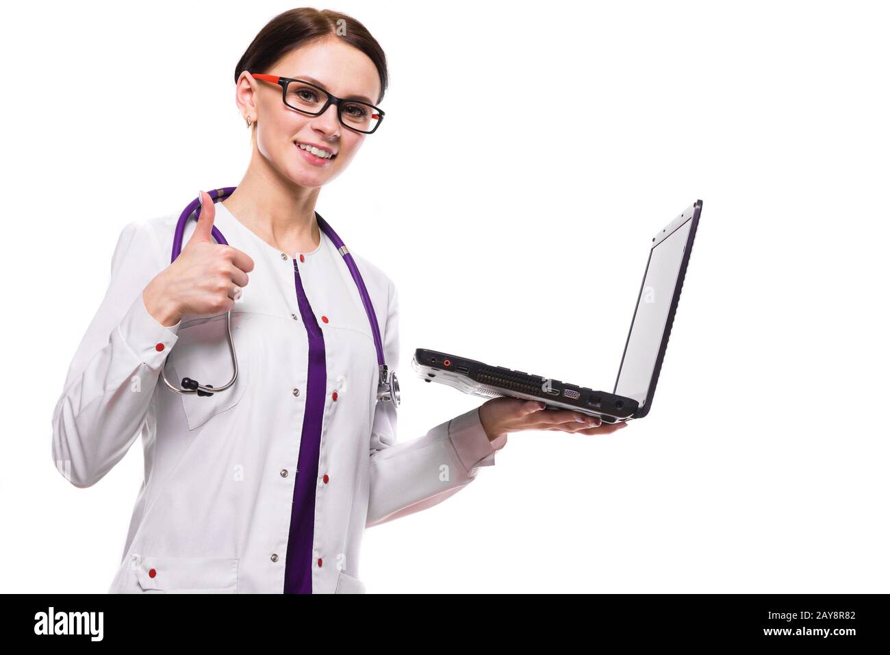 Belle jeune femme médecin holding laptop dans ses mains working on laptop with Thumbs up afficher ok sign on white background Banque D'Images