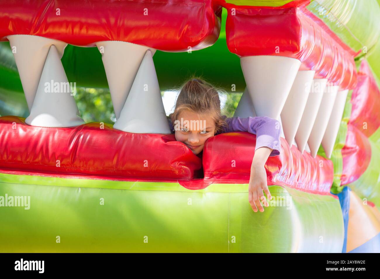 La jeune fille se trouve dans la bouche du dragon sur un trampoline gonflable Banque D'Images