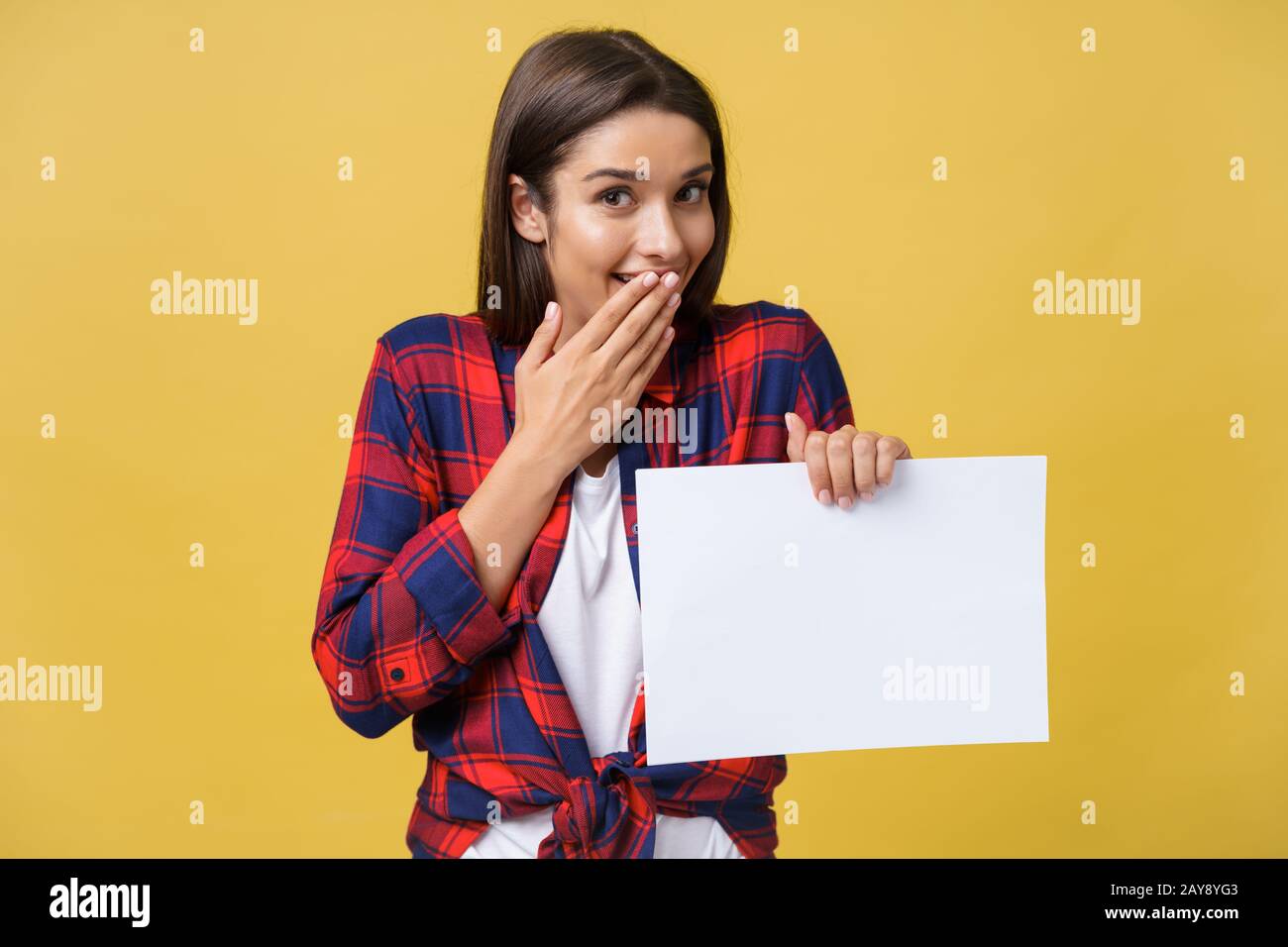 Jeune femme feuille de papier blanc. Studio portrait sur fond jaune. Banque D'Images