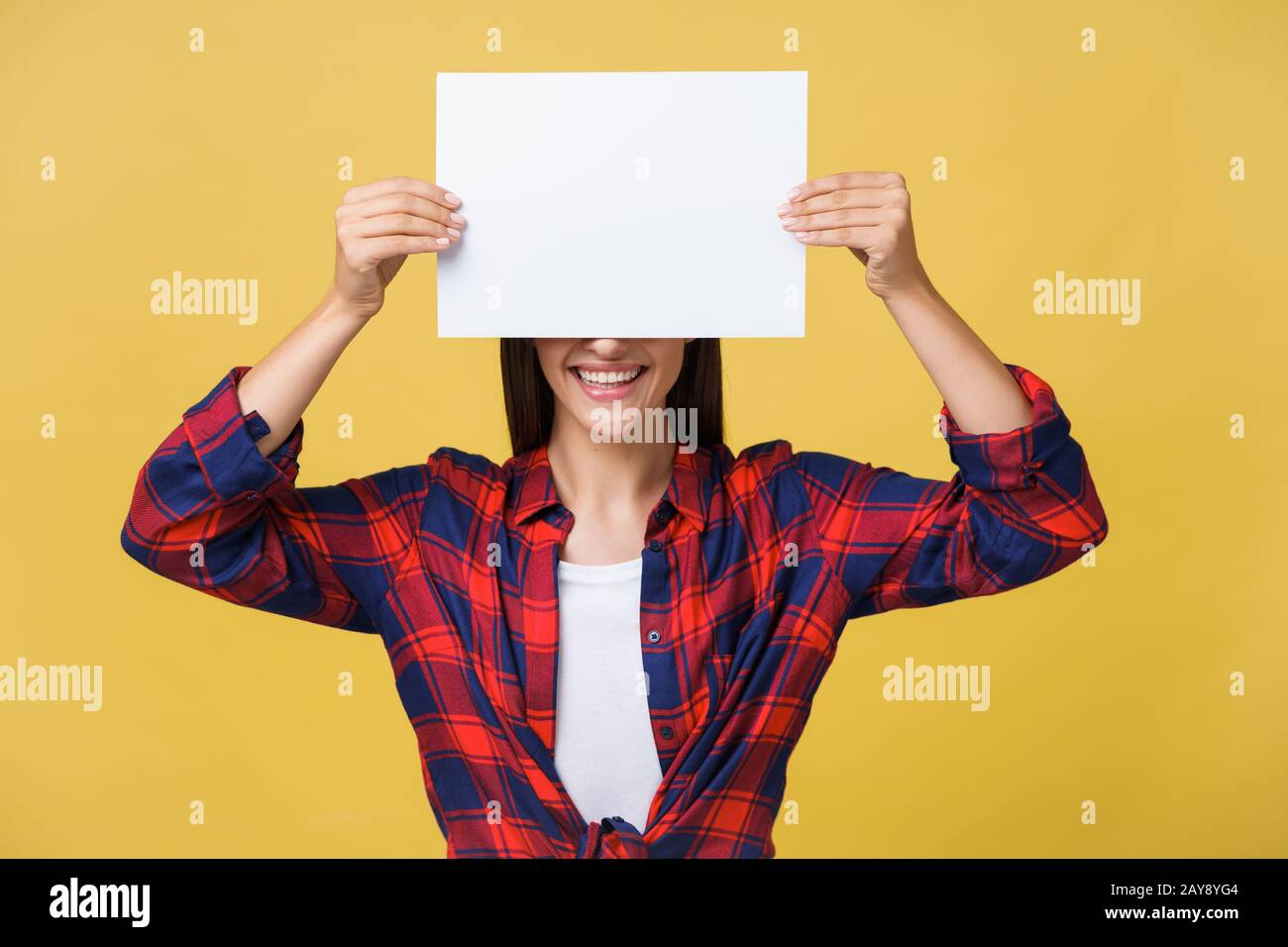 Jeune femme feuille de papier blanc. Studio portrait sur fond jaune. Banque D'Images