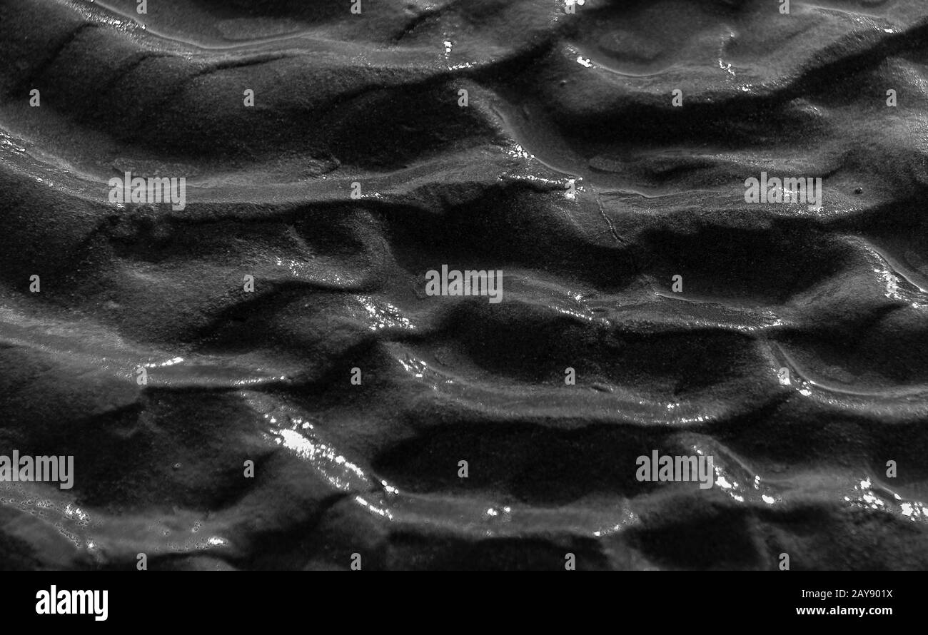 Vagues sur le sable près de la plage en noir et blanc gros plan dans le paysage Banque D'Images