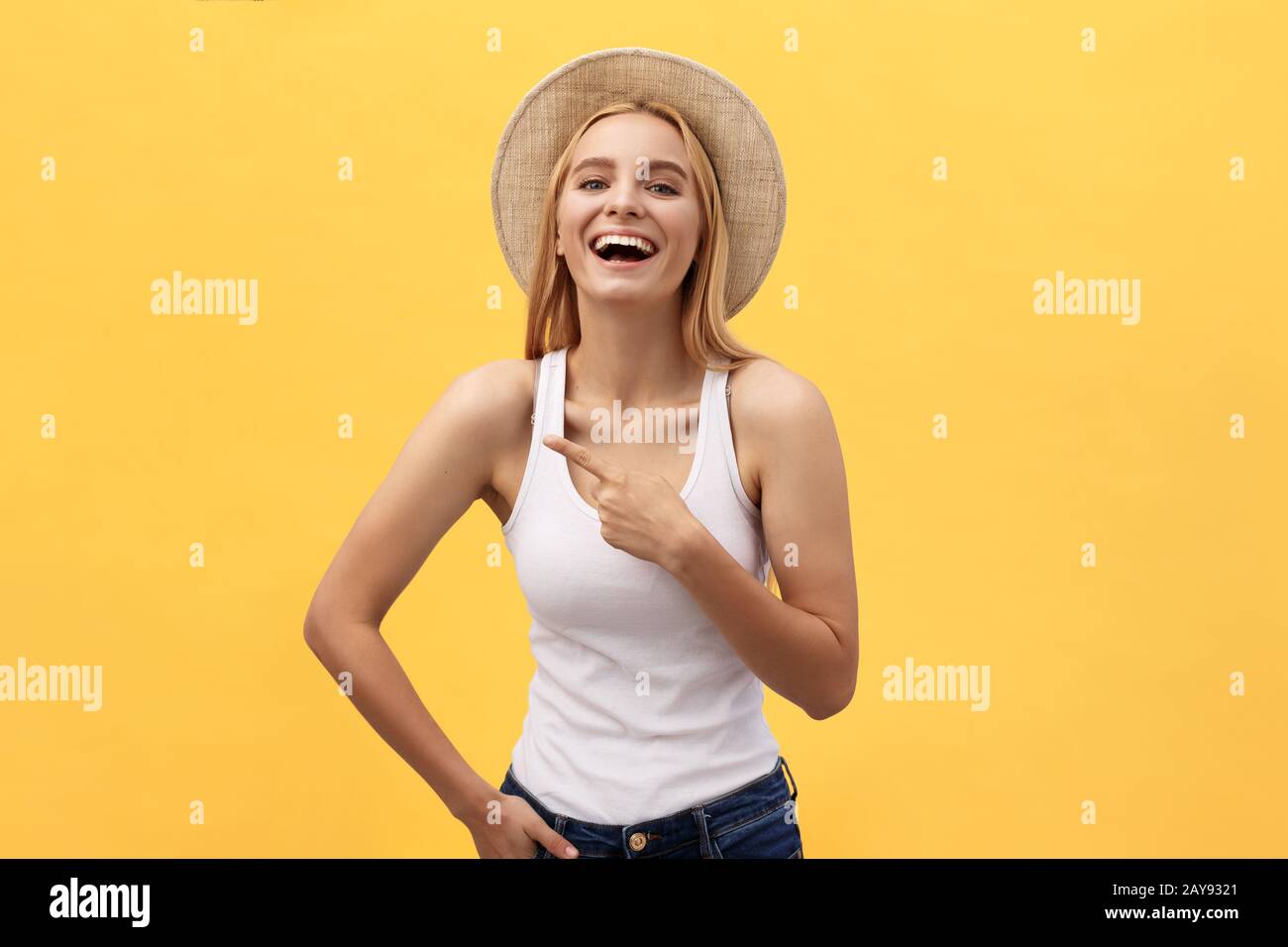 Laughing young Beautiful woman dans t-shirt à la recherche et à l'écart de pointage avec doigt sur fond jaune Banque D'Images