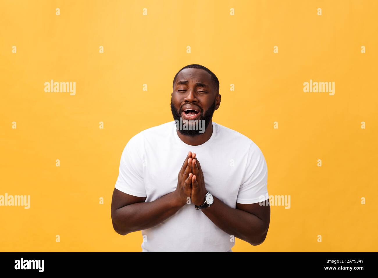 Studio portrait de jeune homme d'Afrique américain en chemise blanche, tenant les mains dans la prière, regardant la caméra avec ske réfléchi Banque D'Images