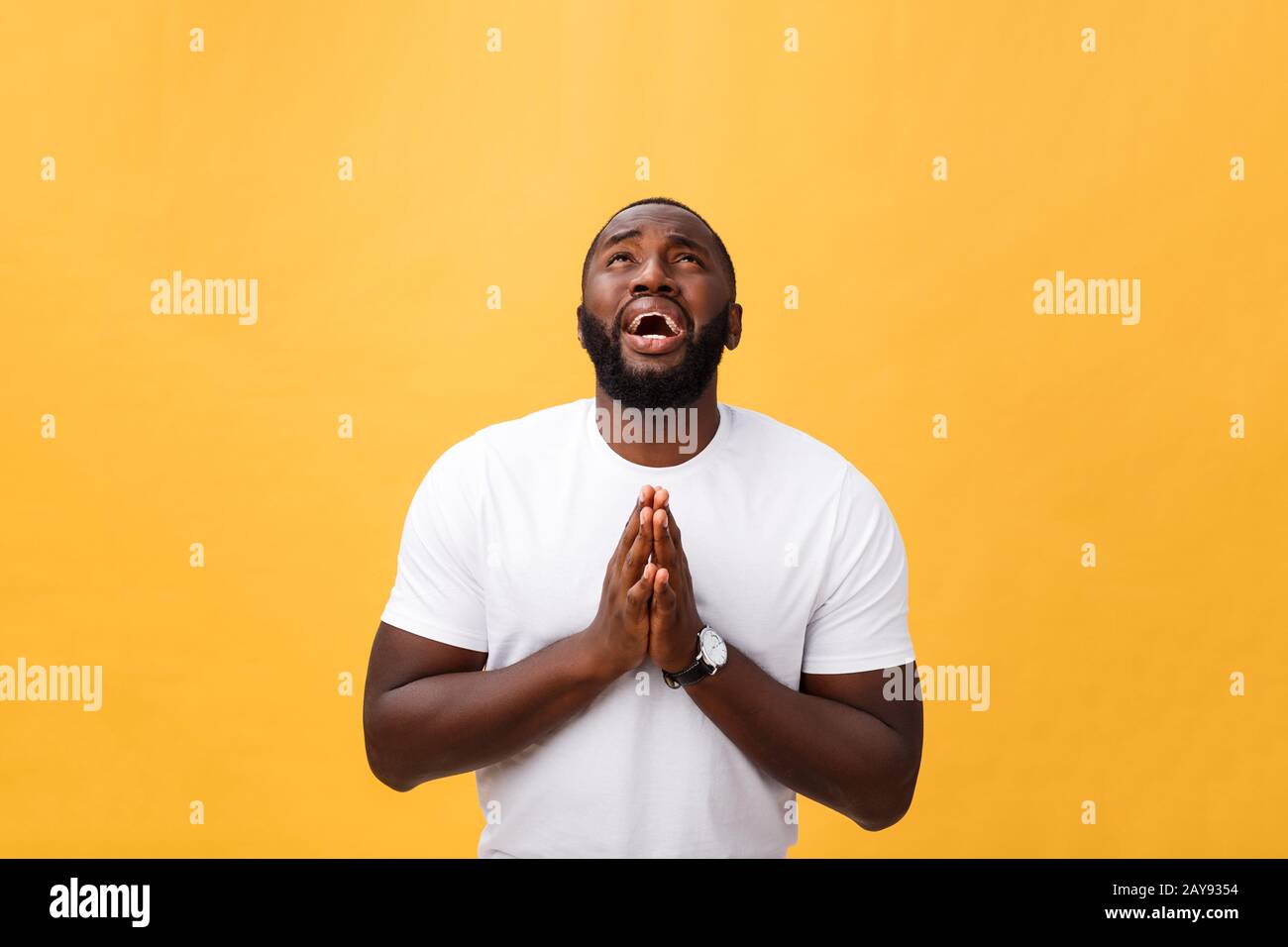 Studio portrait de jeune homme d'Afrique américain en chemise blanche, tenant les mains dans la prière, regardant la caméra avec ske réfléchi Banque D'Images