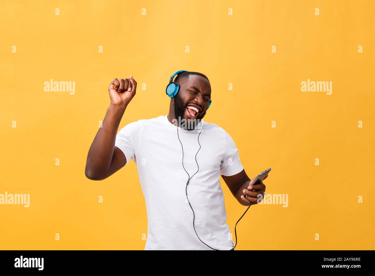 African American man écouter avec le casque et la danse avec la musique. Isolé sur fond jaune Banque D'Images