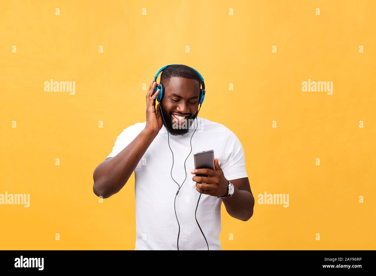 African American man écouter avec le casque et la danse avec la musique. Isolé sur fond jaune Banque D'Images