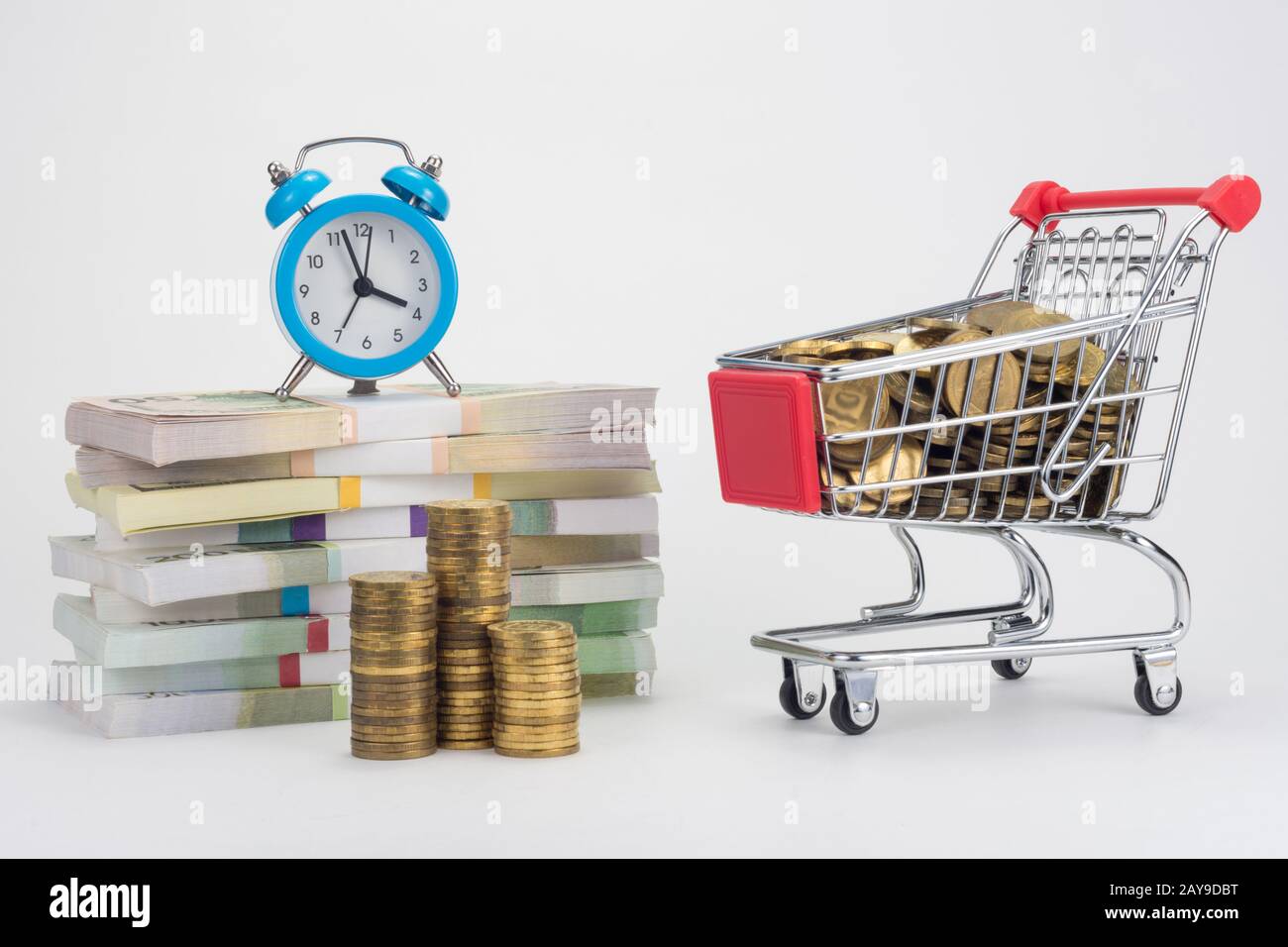 Des piles d'argent, un réveil est sur eux, un chariot avec des pièces Banque D'Images