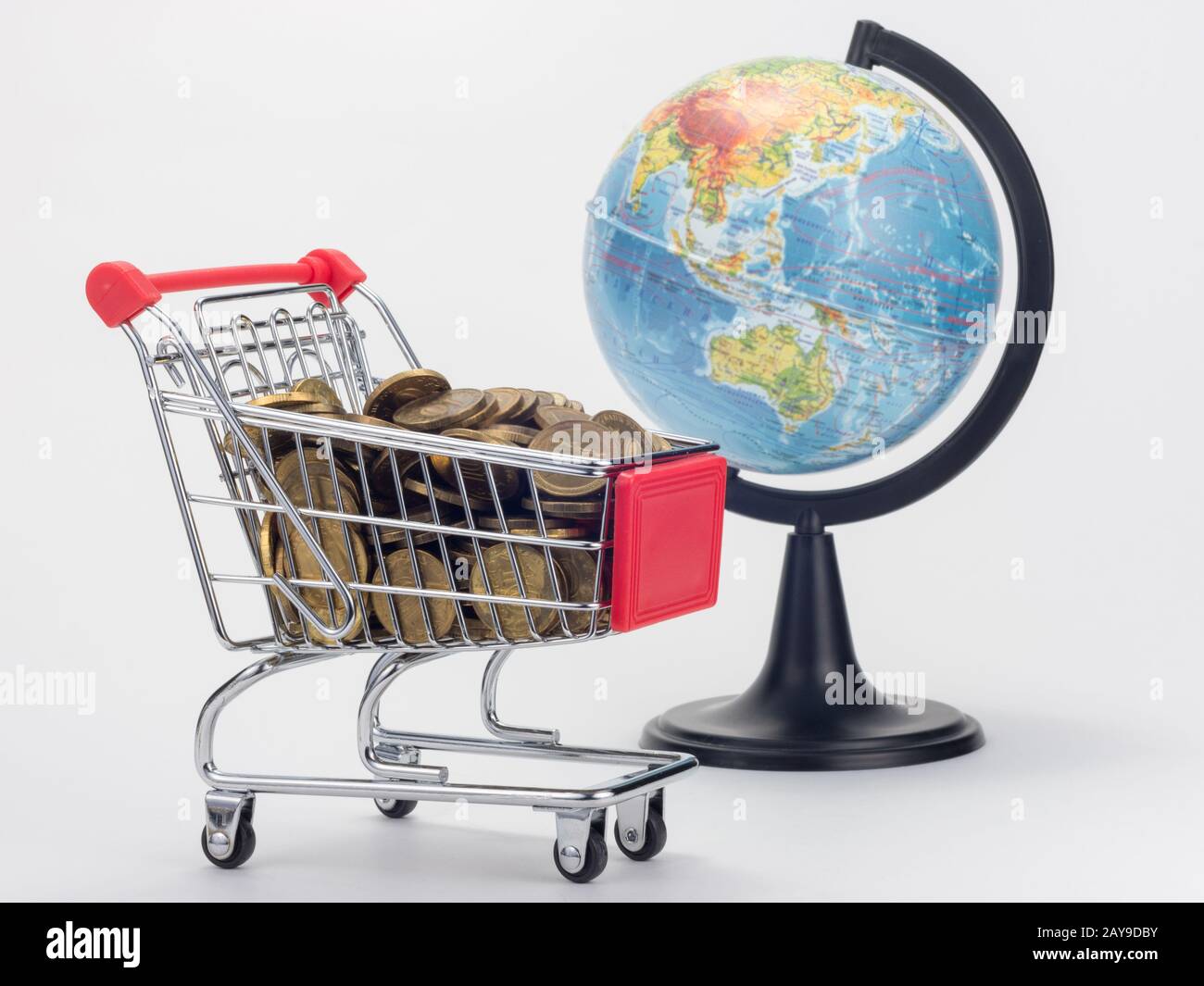 Chariot d'épicerie rempli de pièces de monnaie, dans l'arrière-plan est un globe Banque D'Images