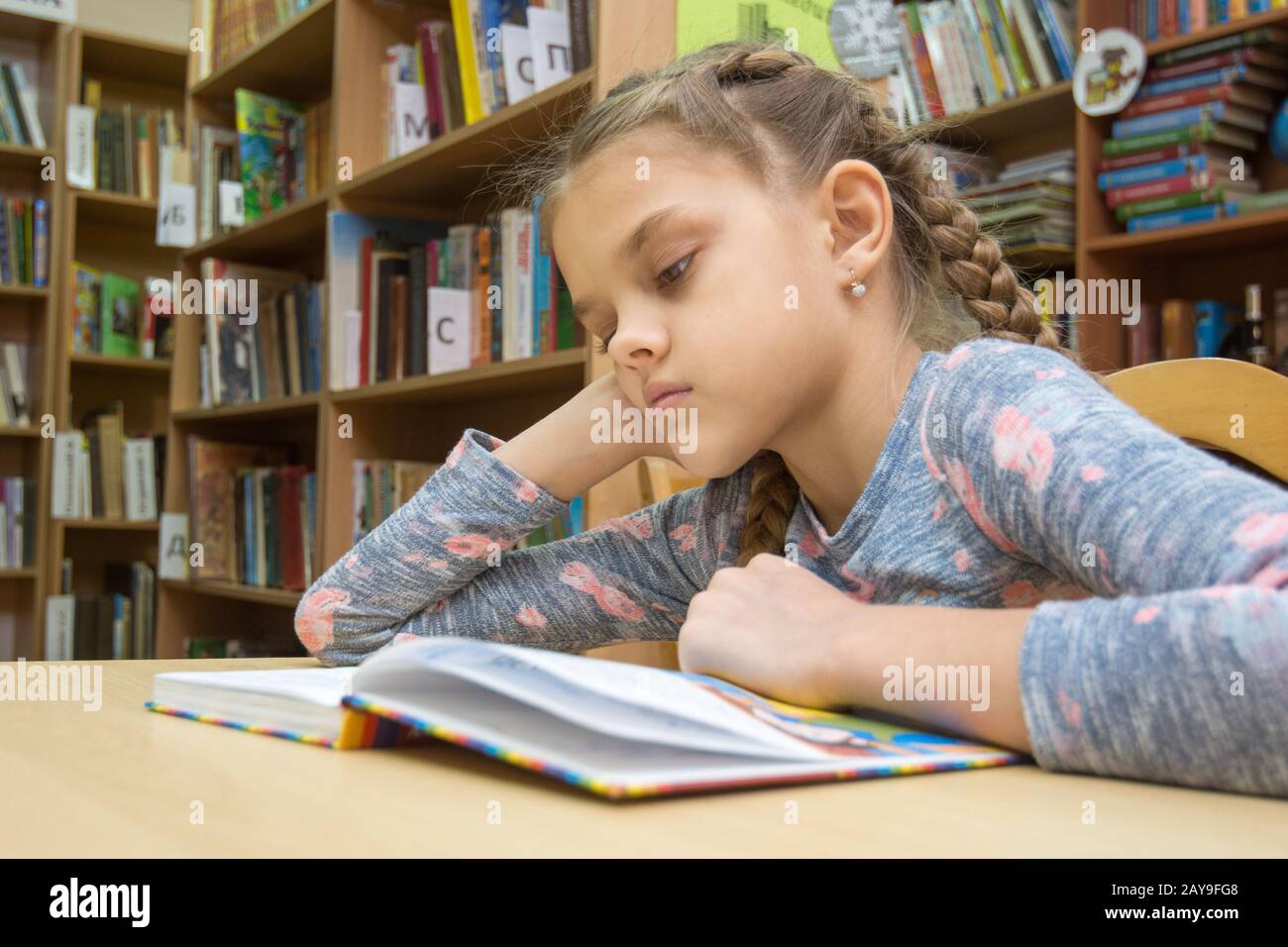 Une fille de dix ans est en train de lire un livre dans la salle de lecture Banque D'Images