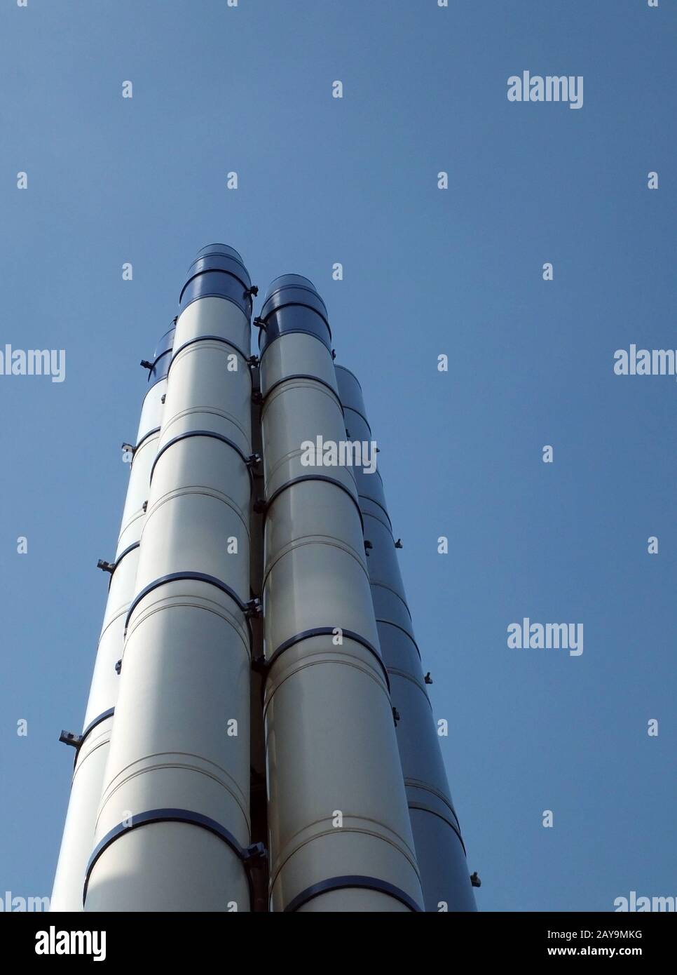 un groupe de grands cheminées industrielles en acier moderne, debout contre un ciel bleu vif Banque D'Images