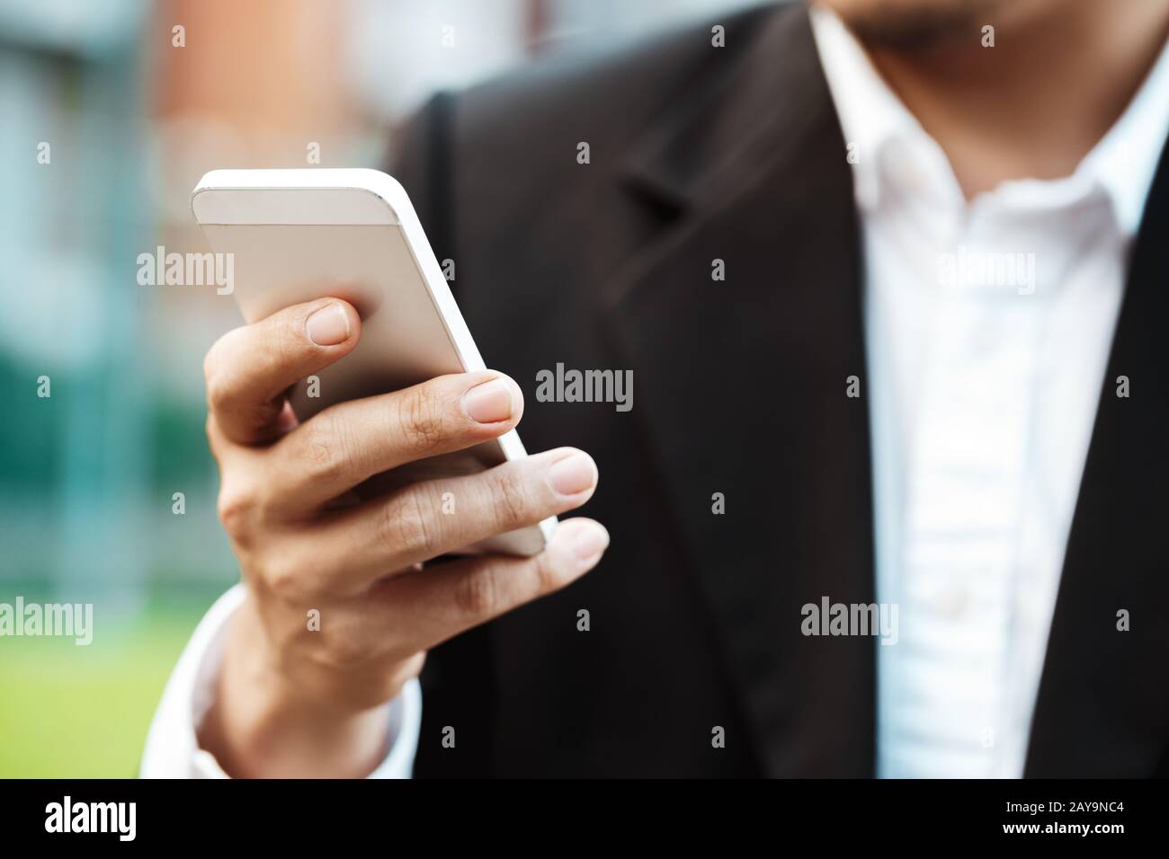 Close-up Smart Business moderne homme portant costume noir et chemise blanche et SMS sur téléphone intelligent. Banque D'Images