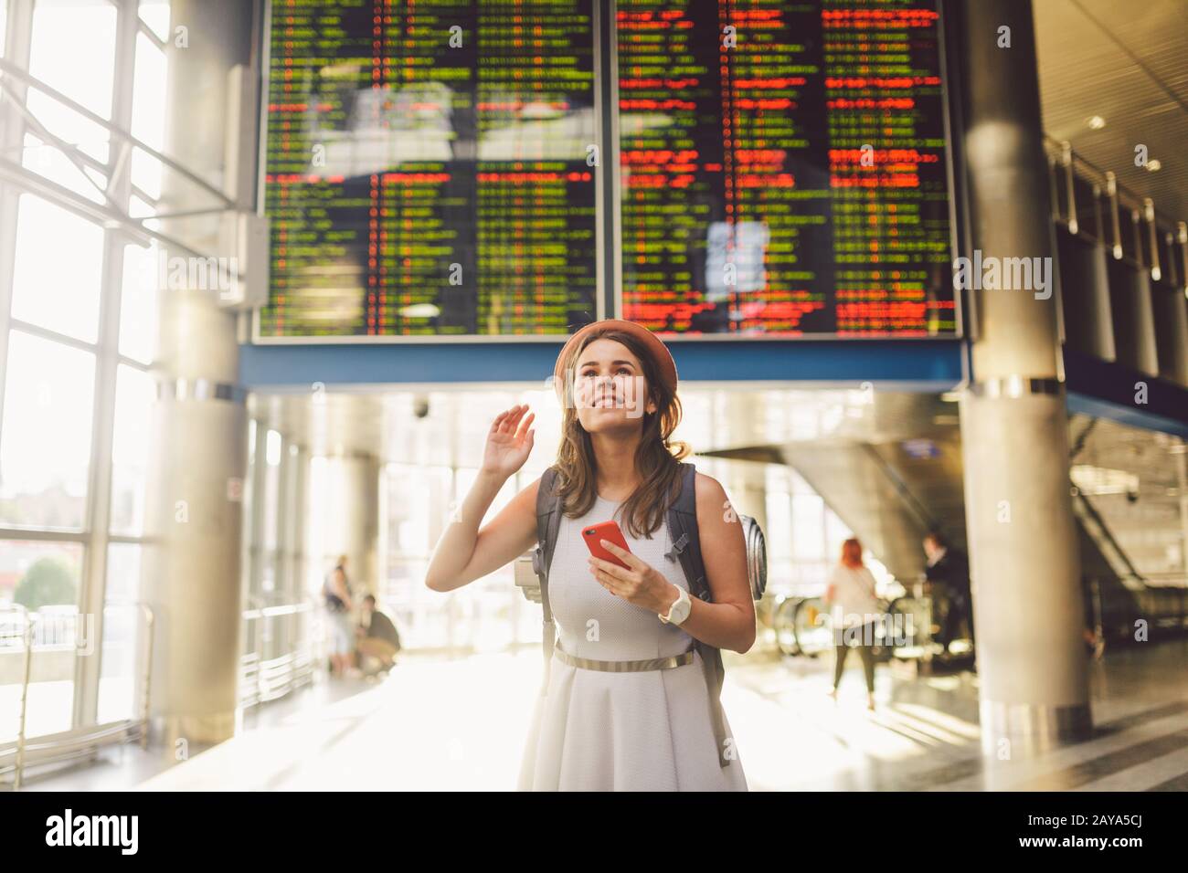 Voyage à thème et tranosport. Belle jeune femme caucasienne en robe et sac à dos debout à l'intérieur de la gare ou terminal loo Banque D'Images