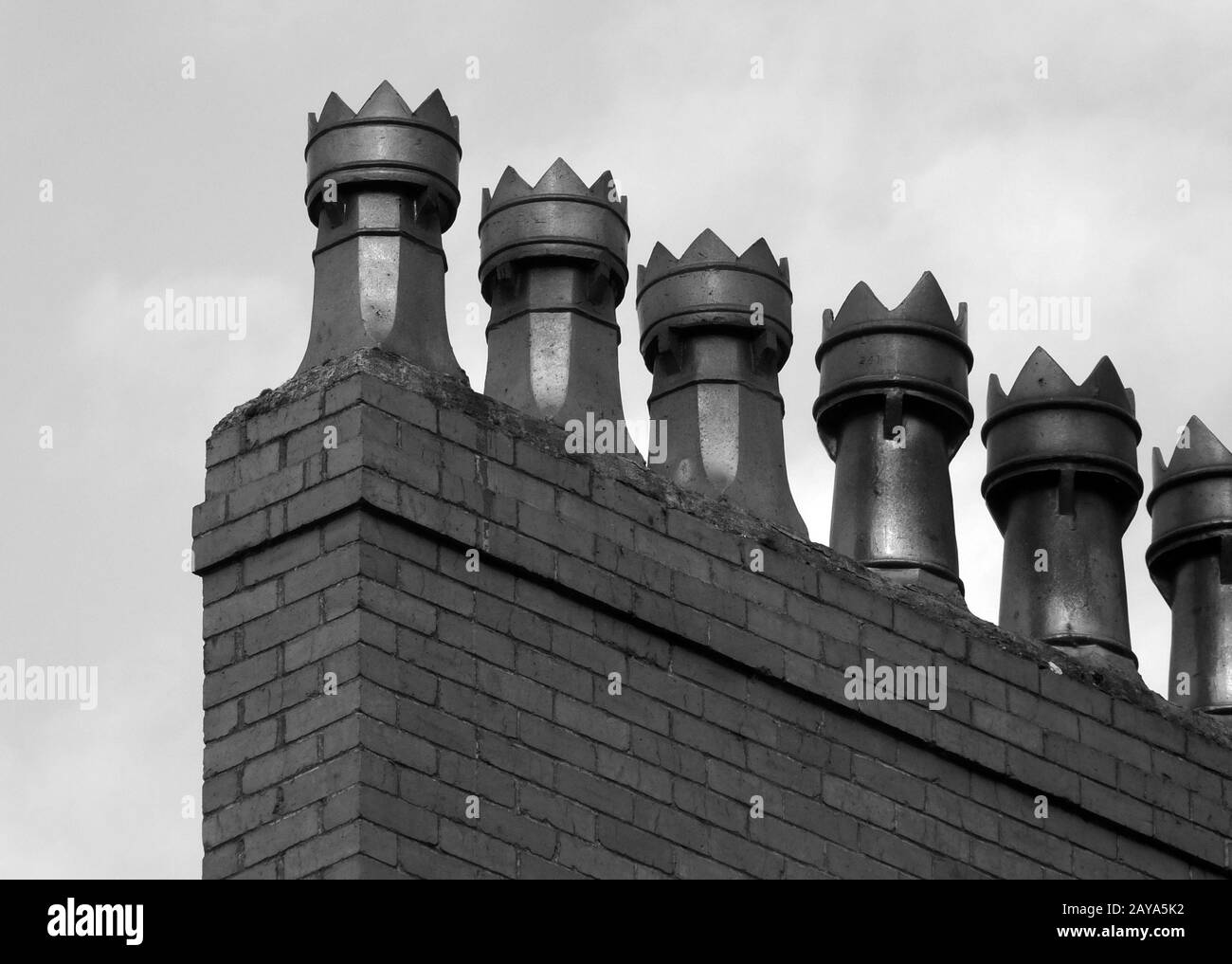 image monochrome d'une rangée de pots de cheminée à l'ancienne sur une maison en brique Banque D'Images
