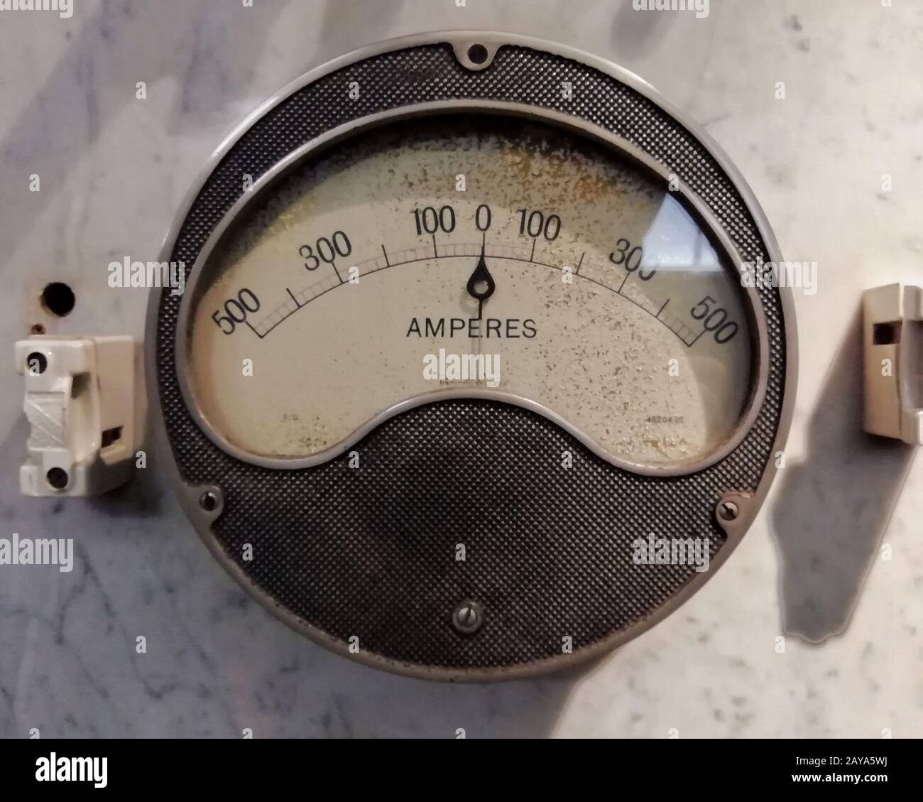 un grand ampèremètre industriel rond vintage avec cadran analogique avec numéros avec symboles électriques standard sur cadran blanc activé Banque D'Images