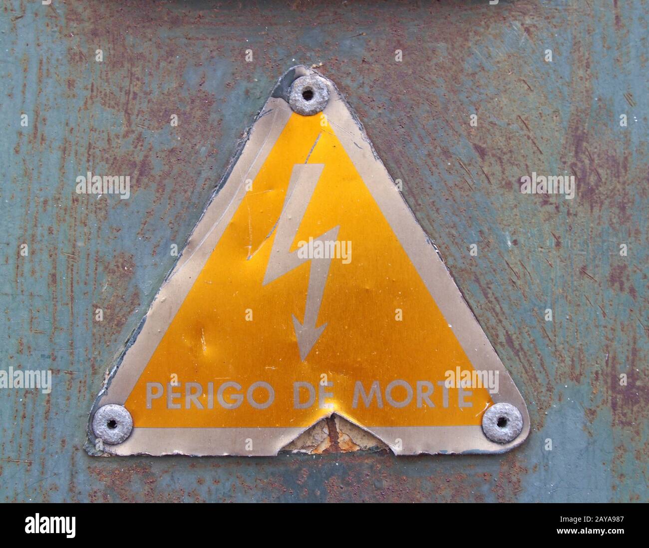 Un vieux métal triangulaire jaune portugais signe de sécurité de l'électricité avec un symbole lumineux perigo de morte - transla Banque D'Images