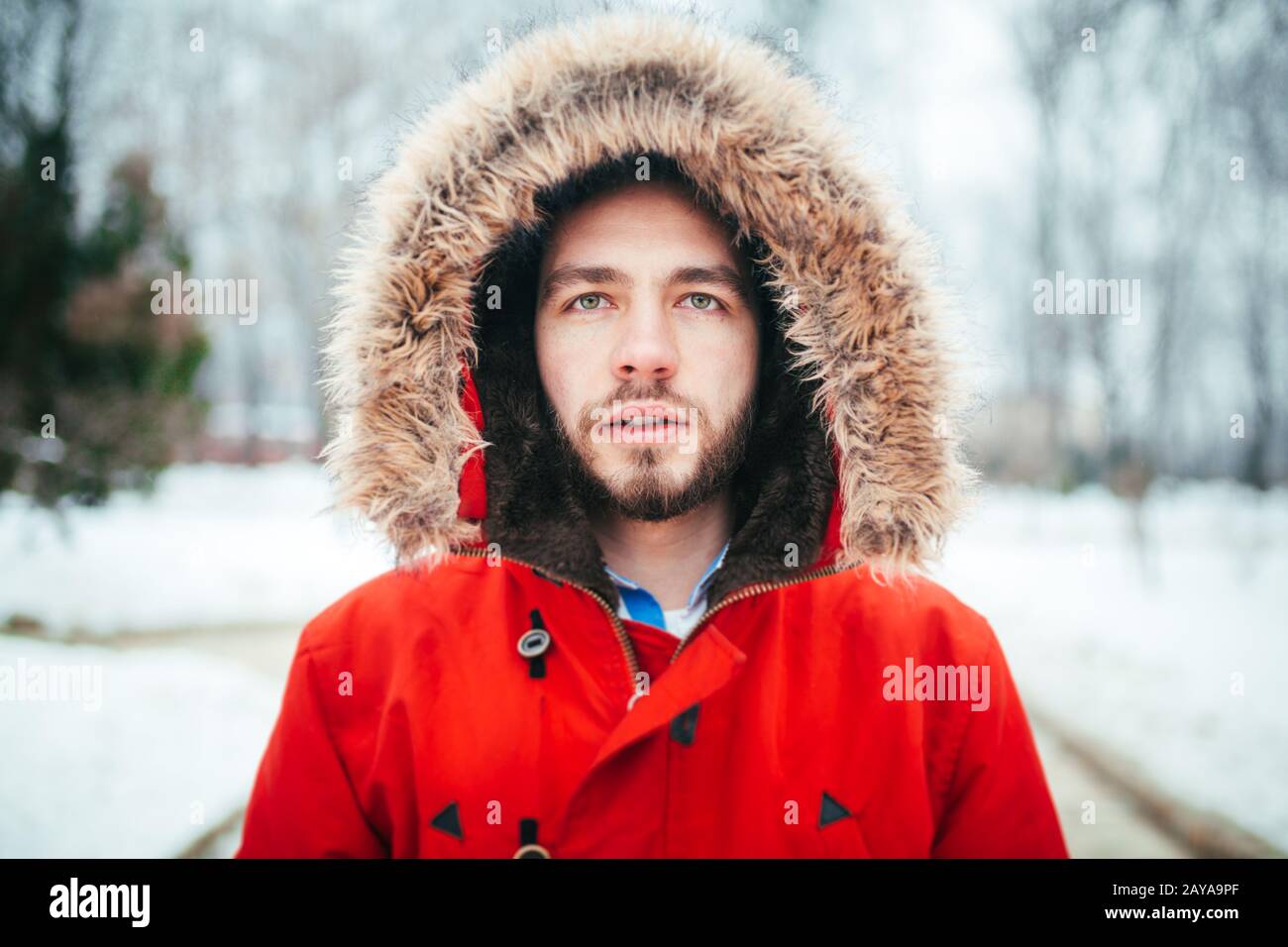 Portrait, gros plan d'un jeune homme élégant avec une barbe vêtue d'une  veste d'hiver rouge avec une capuche et une fourrure sur ses tribunes aga  Photo Stock - Alamy
