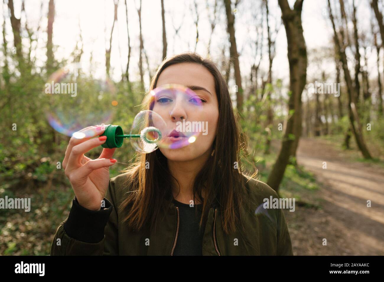 Jeune femme soufflant des bulles dans les bois Banque D'Images