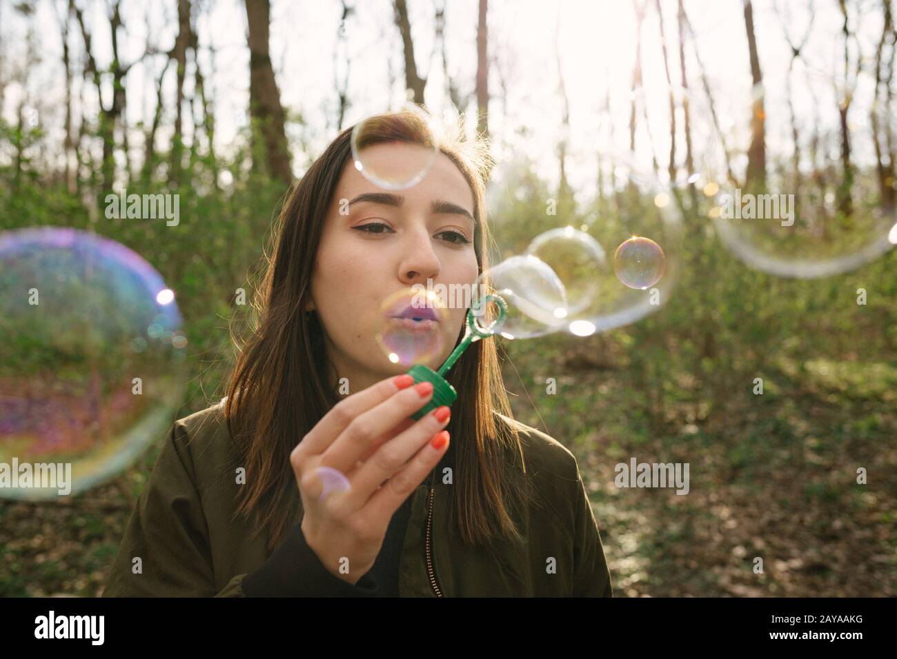 Jeune femme soufflant des bulles de savon dans les bois. Banque D'Images