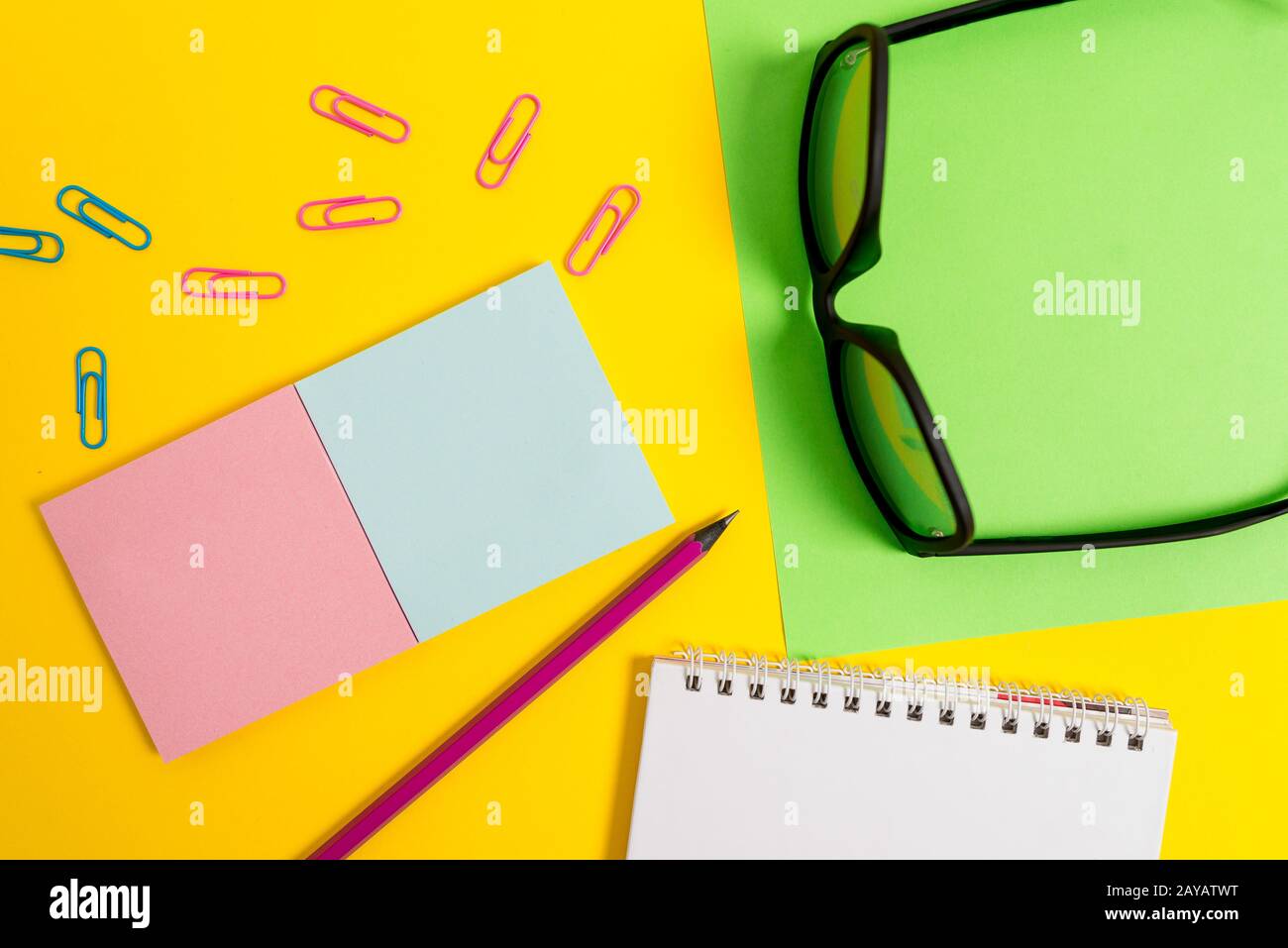 Face vue de couleur vierge spirale blocs-notes clips crayon lunettes de vue arrière-plan de couleur unie. Texte vide événements futurs importants. WHA Banque D'Images