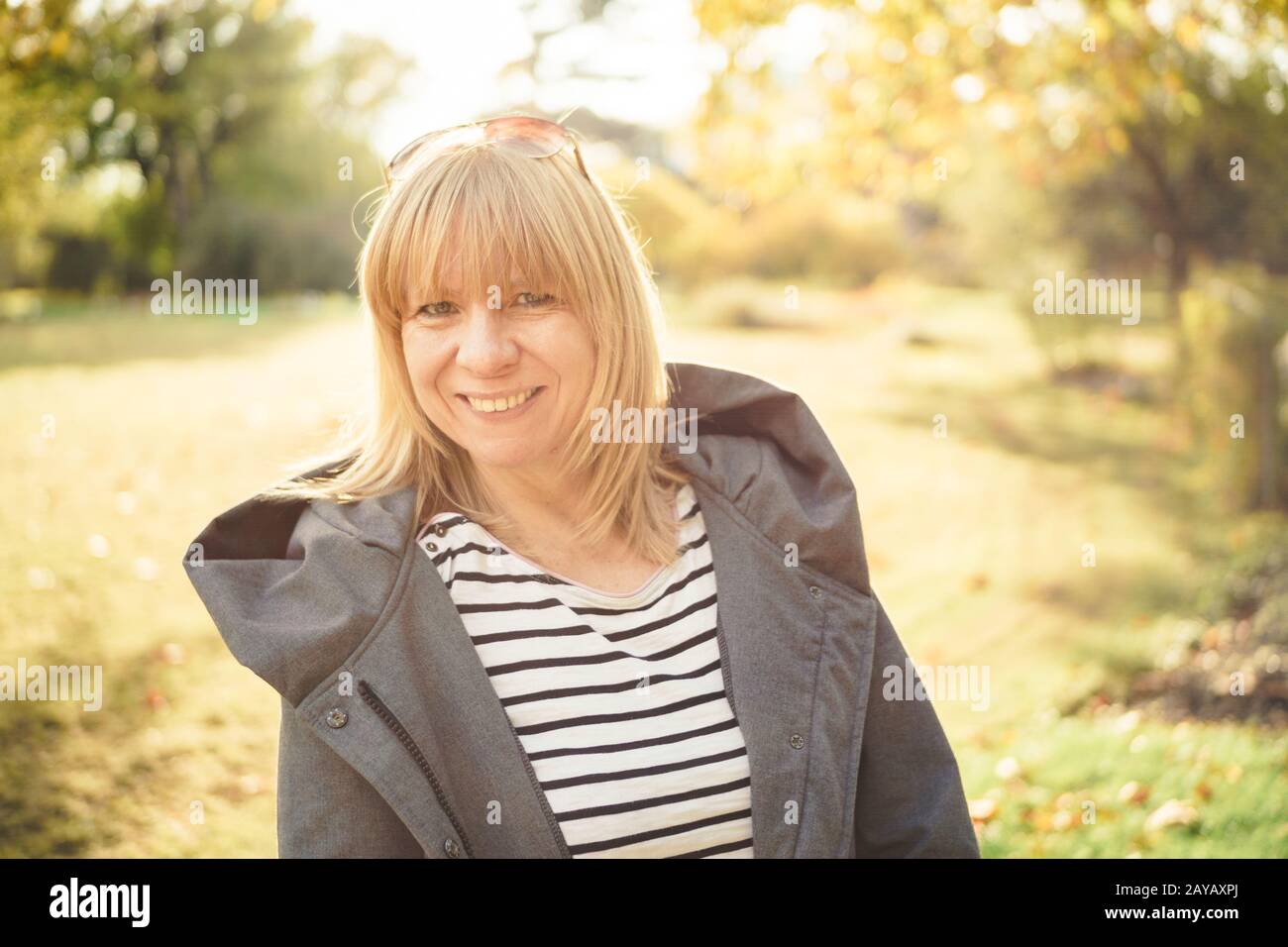 Femme blonde naturelle se tenant dans un parc d'automne. Automne Banque D'Images