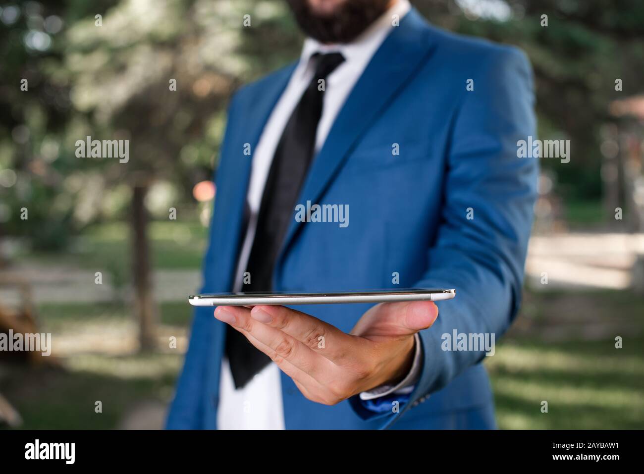 Concept d'entreprise avec un homme tenant un téléphone mobile avec écran tactile. Homme d'affaires tient le dessus de tour dans sa main. Homme d'affaires en bleu sui Banque D'Images