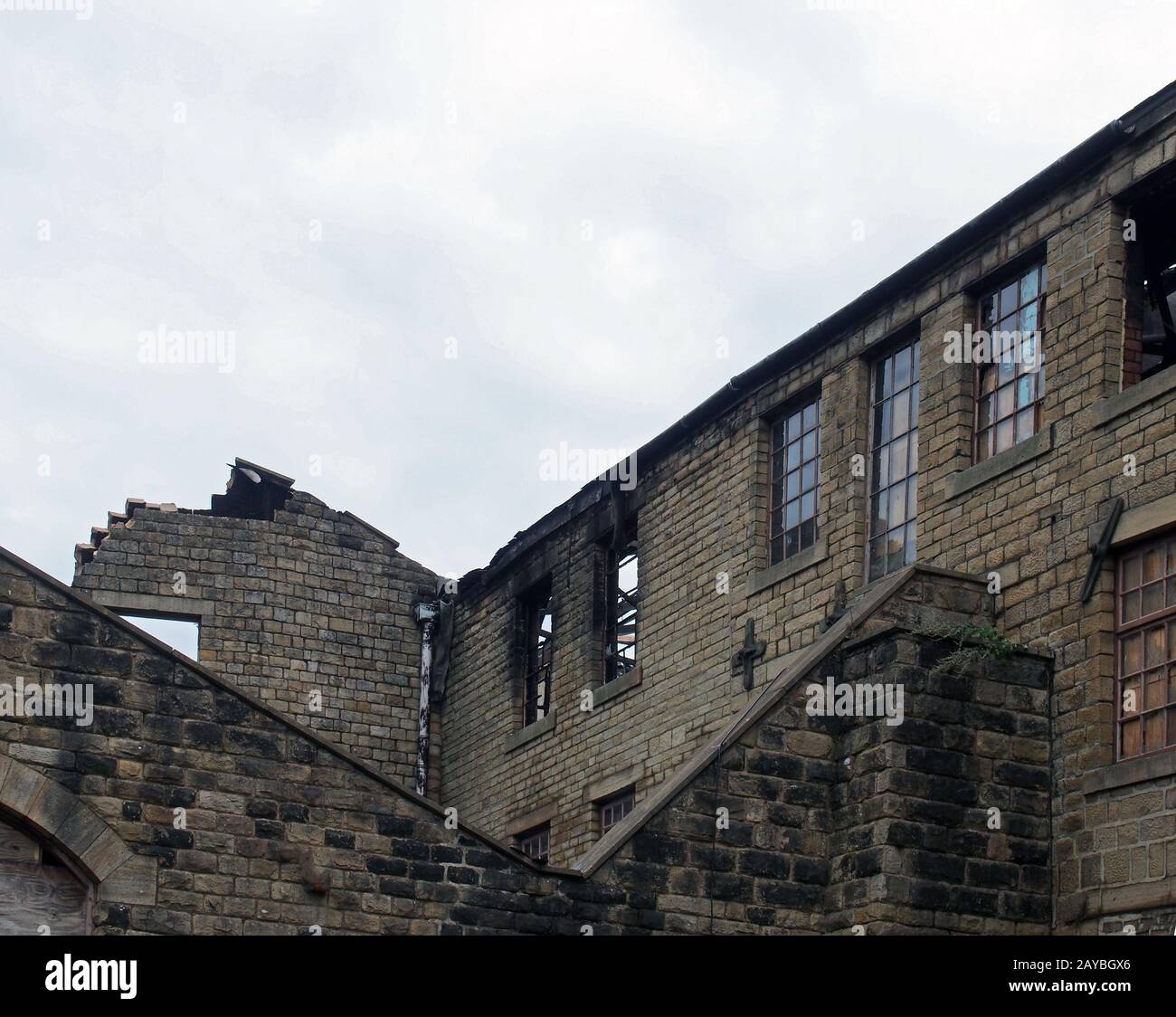 un vieux bâtiment industriel abandonné ruiné avec des fenêtres cassées incendiées qui s'effondrent les murs Banque D'Images