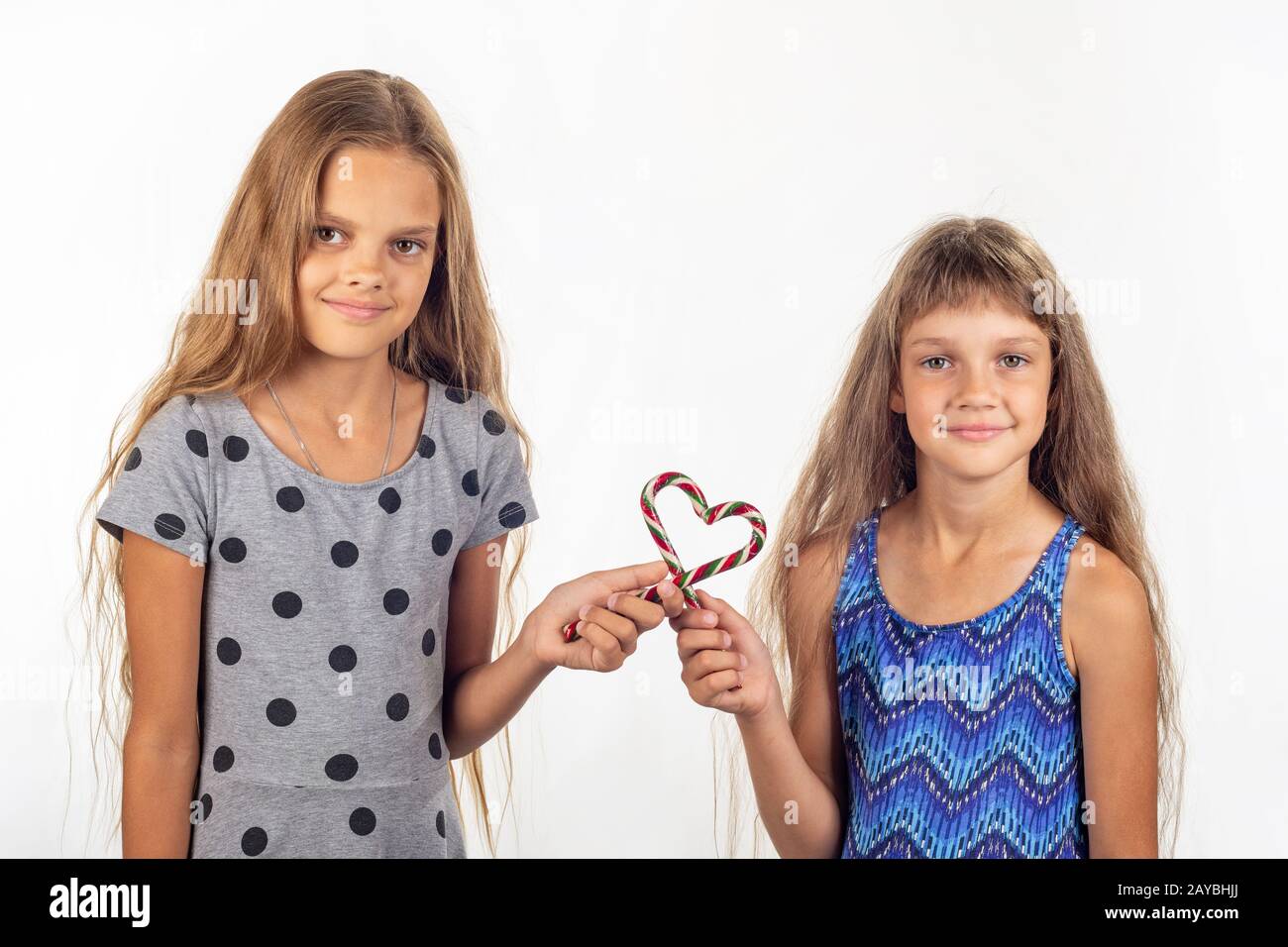 Deux jeunes filles a fait un coeur de deux sucettes et regarder dans le cadre Banque D'Images
