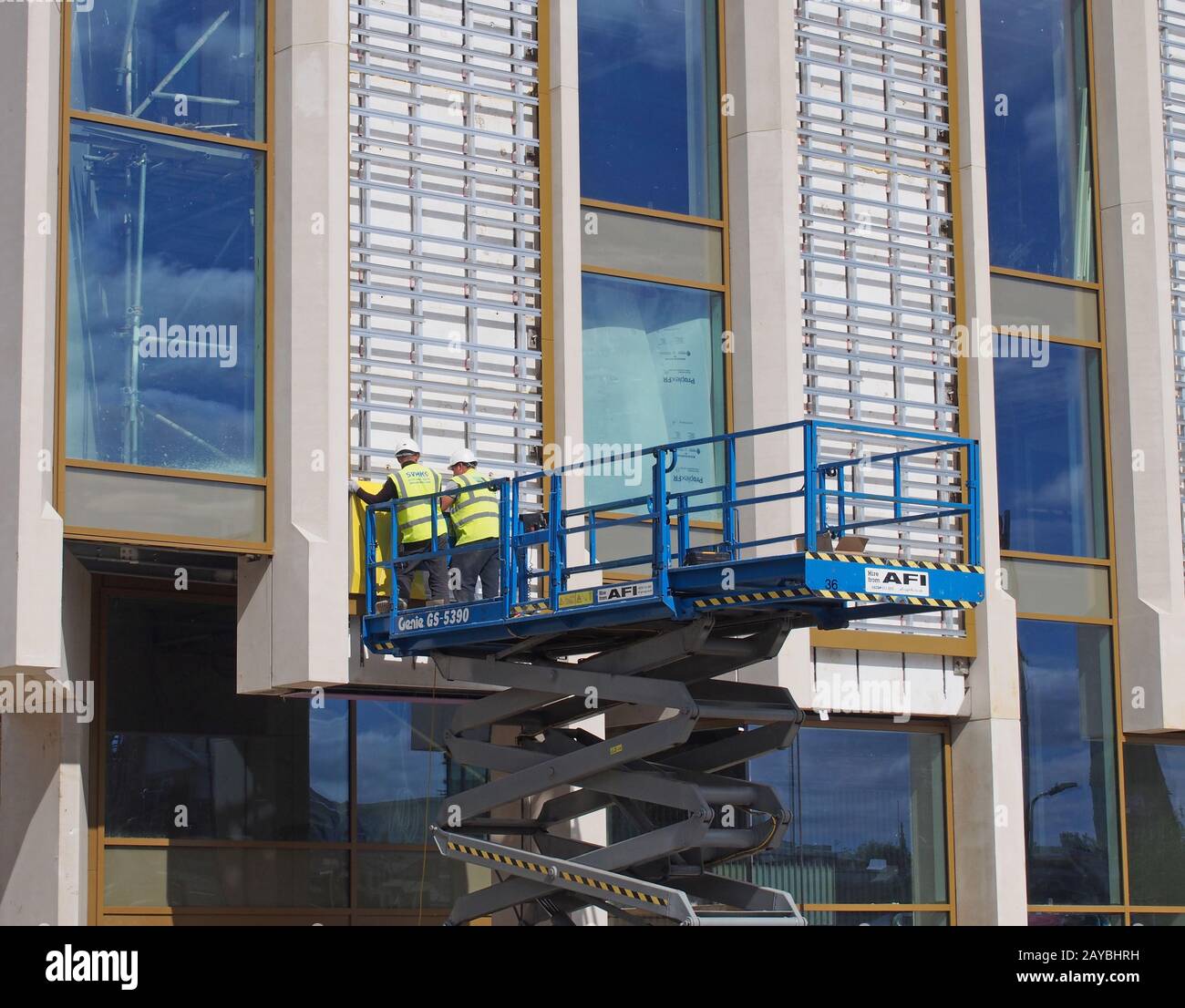 deux hommes dans des vêtements de protection travaillant sur une plate-forme de construction surélevée sur un chantier Banque D'Images