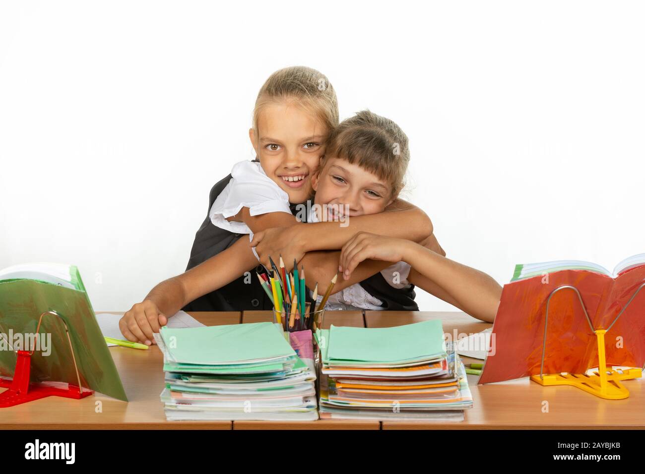Deux écolières sont assis à un bureau à la recherche de manuels scolaires Banque D'Images