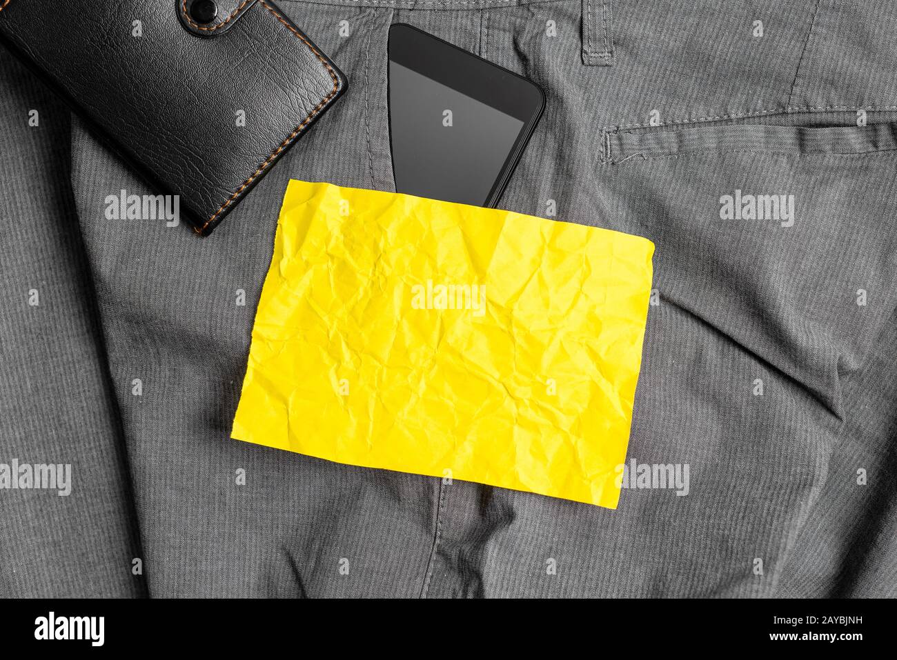 Smartphone dans la poche avant du pantalon avec porte-monnaie et papier à note jaune. Le gadget moderne est placé à l'intérieur du pantalon homme nea Banque D'Images